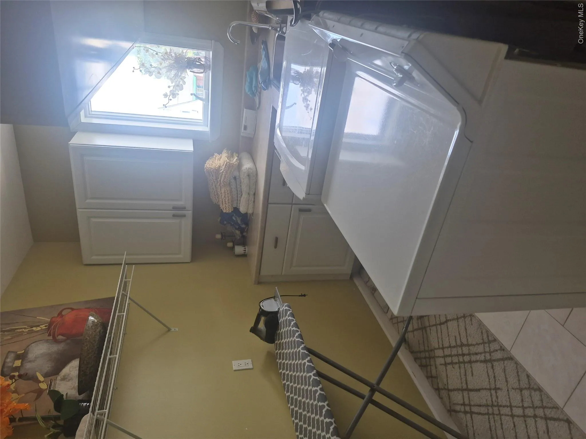 Laundry area with light-colored cabinetry, a utility sink, and a window with washer/dryer combo. Laundry area with light-colored cabinetry, a utility sink, and a window with washer/dryer combo.
