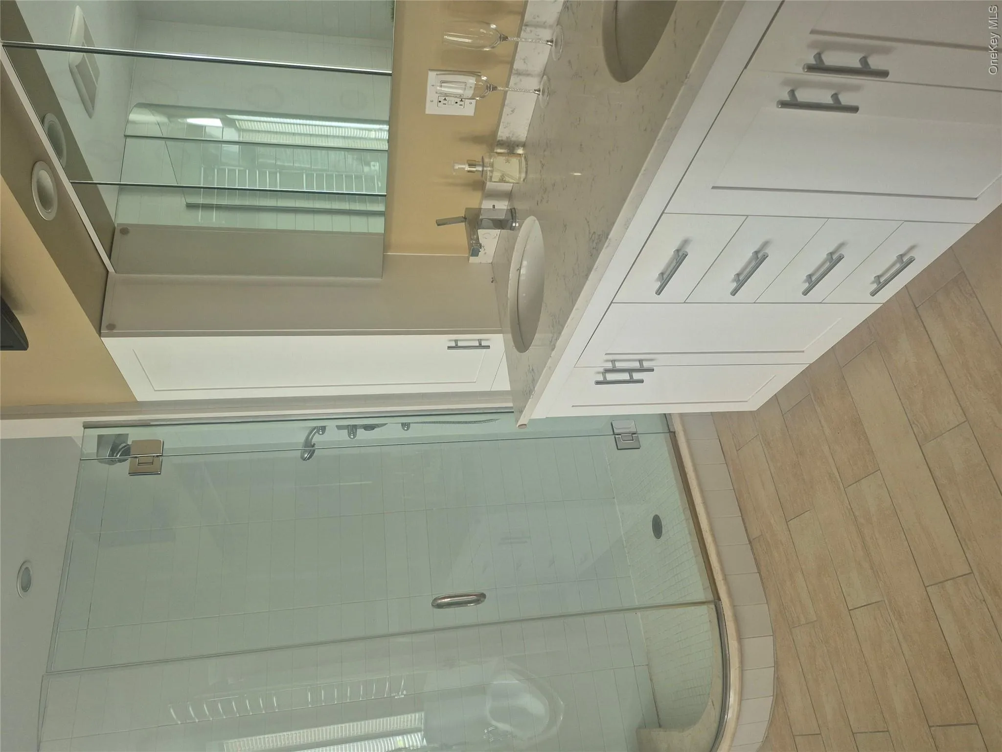 Master Bathroom with double vanity with integrated sinks, white cabinetry and light-toned countertop, mirrored medicine cabinet and stand-alone glass encased walk-in shower Master Bathroom with double vanity with integrated sinks, white cabinetry and light-toned countertop, mirrored medicine cabinet and stand-alone glass encased walk-in shower