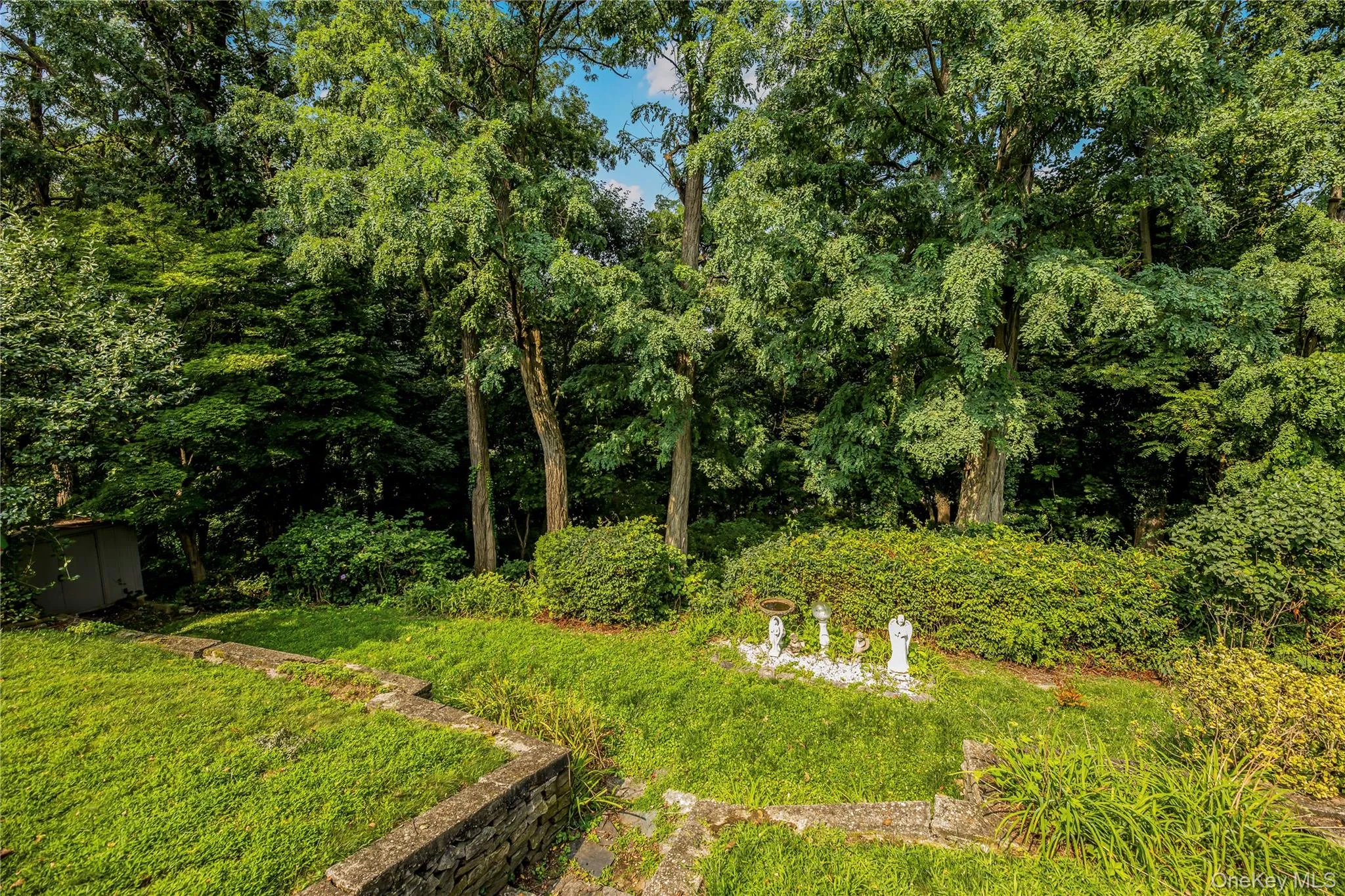 Expansive terraced yard with established trees, lush shrubbery, and stone retaining walls Expansive terraced yard with established trees, lush shrubbery, and stone retaining walls