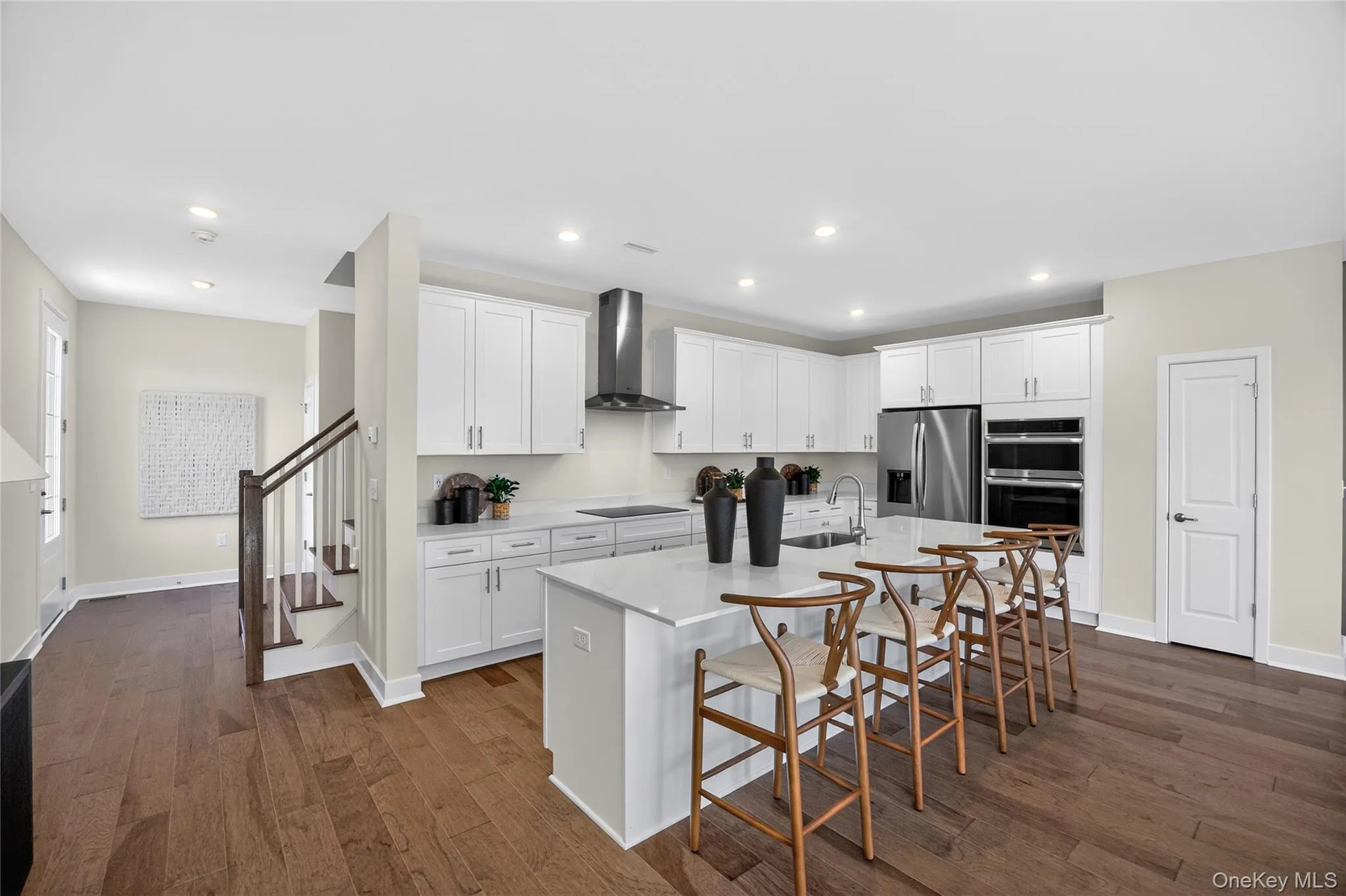 Open-concept kitchen featuring white cabinetry, stainless steel appliances, and a large island with seating. Open-concept kitchen featuring white cabinetry, stainless steel appliances, and a large island with seating.