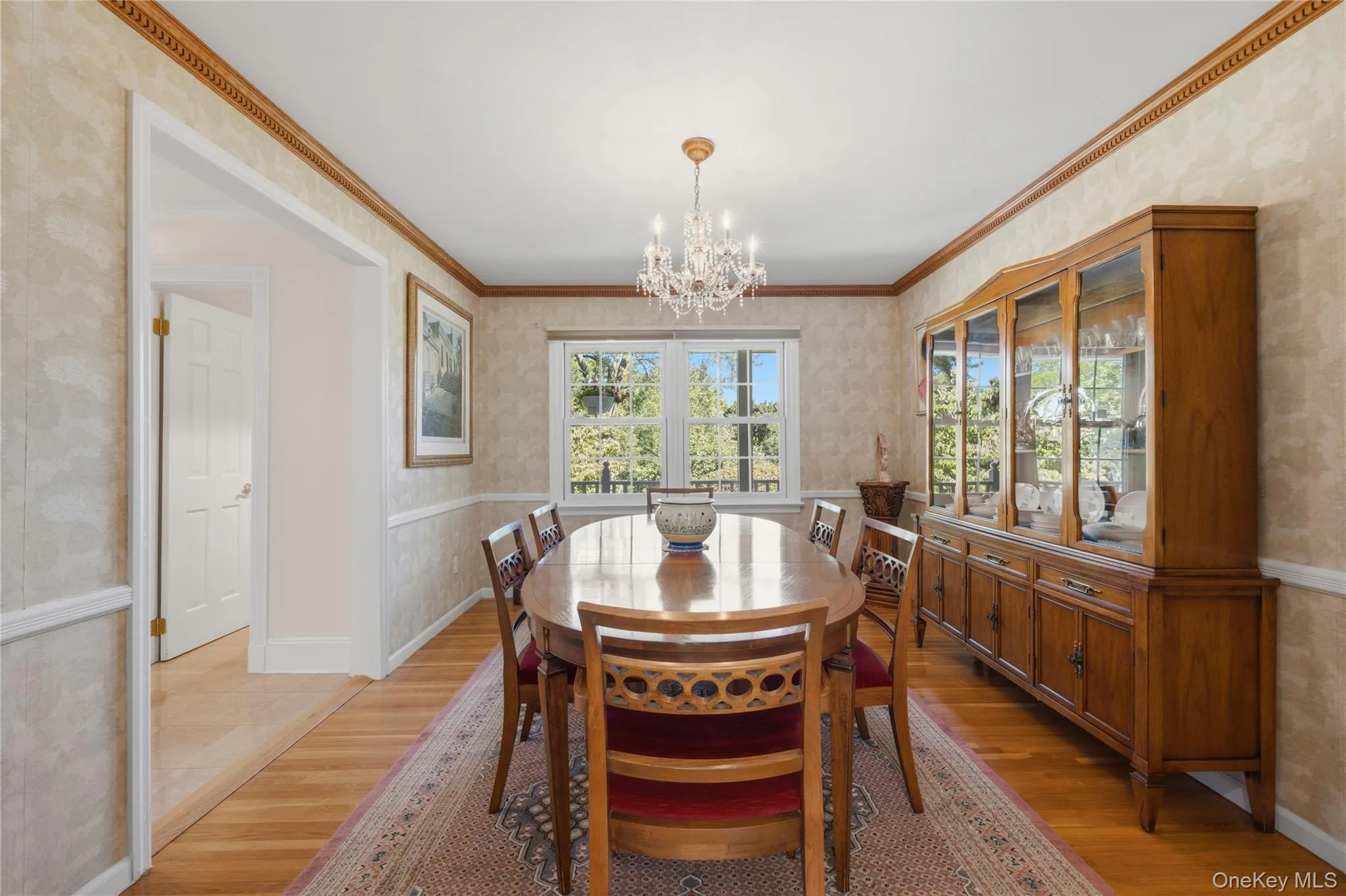 Alternate view of the large Dining Room hardwood floors, chair rail molding, dentil crown molding, Harvey windows, and a swinging door to the Kitchen Alternate view of the large Dining Room hardwood floors, chair rail molding, dentil crown molding, Harvey windows, and a swinging door to the Kitchen
