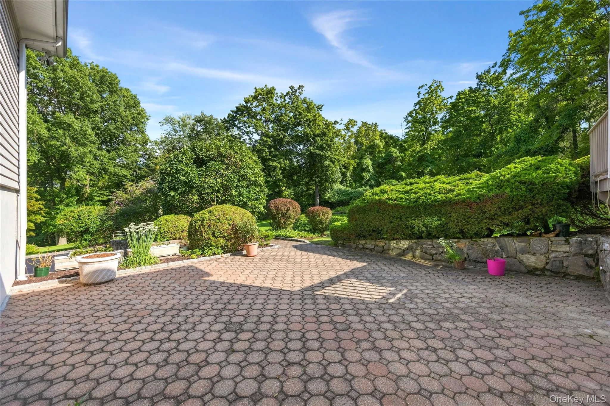 In addition to the rear deck is this enormous paver patio leading to the over acre level yard. Stone wall accents the patio. In addition to the rear deck is this enormous paver patio leading to the over acre level yard. Stone wall accents the patio.
