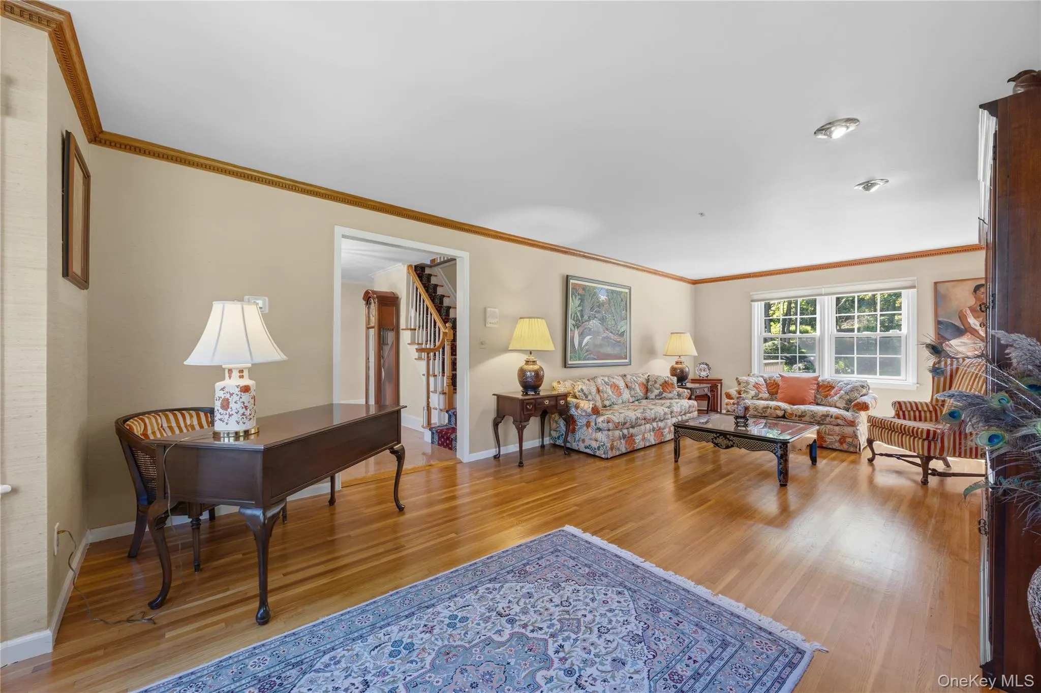 The front-to-back Living Room boasts dentil crown molding, hardwood floors, custom shades (2026), grass cloth wall paper and high lights. The front-to-back Living Room boasts dentil crown molding, hardwood floors, custom shades (2026), grass cloth wall paper and high lights.