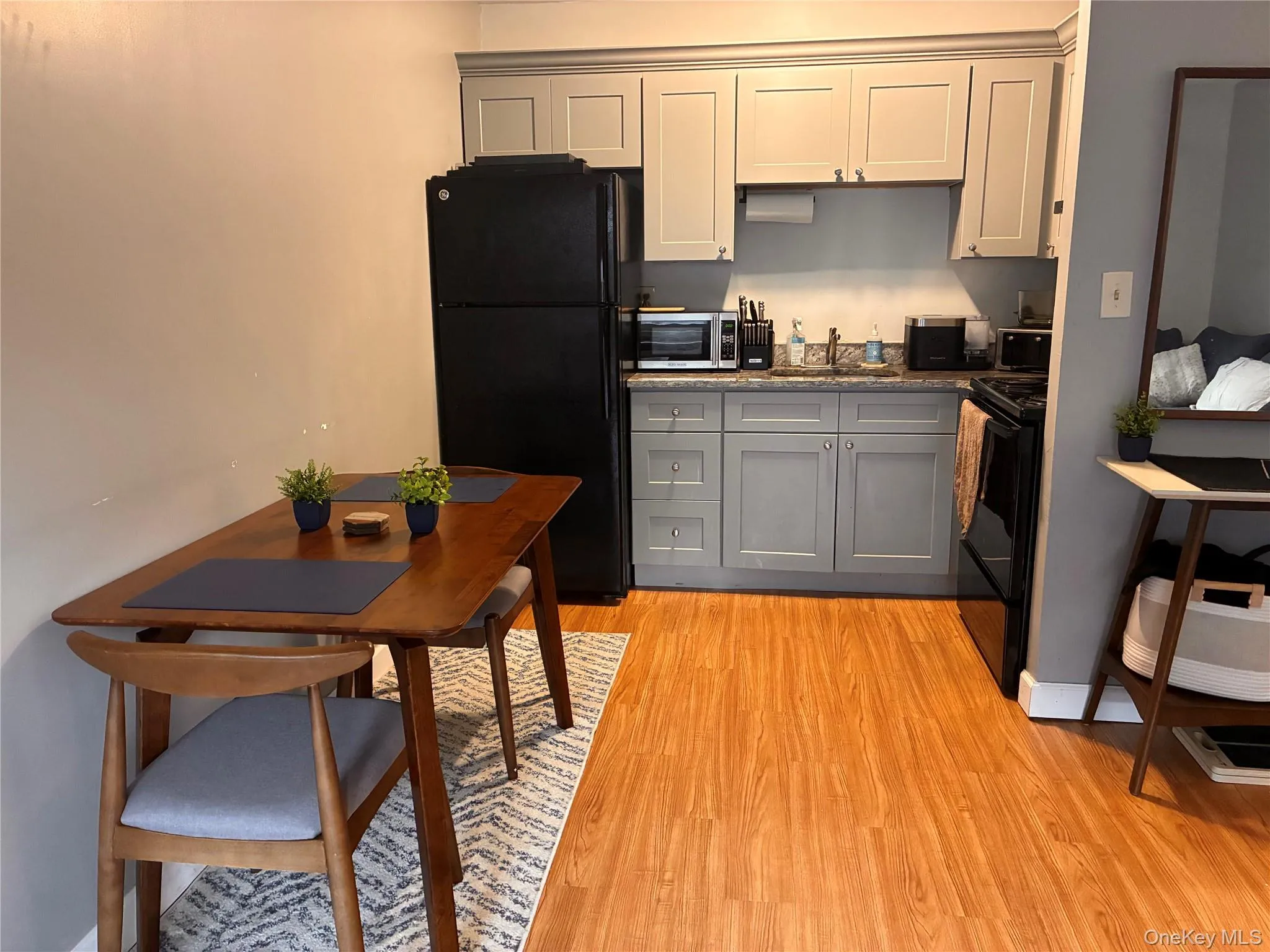 Kitchen featuring light gray cabinetry, a stainless steel sink, black appliances, two person table and laminate flooring Kitchen featuring light gray cabinetry, a stainless steel sink, black appliances, two person table and laminate flooring