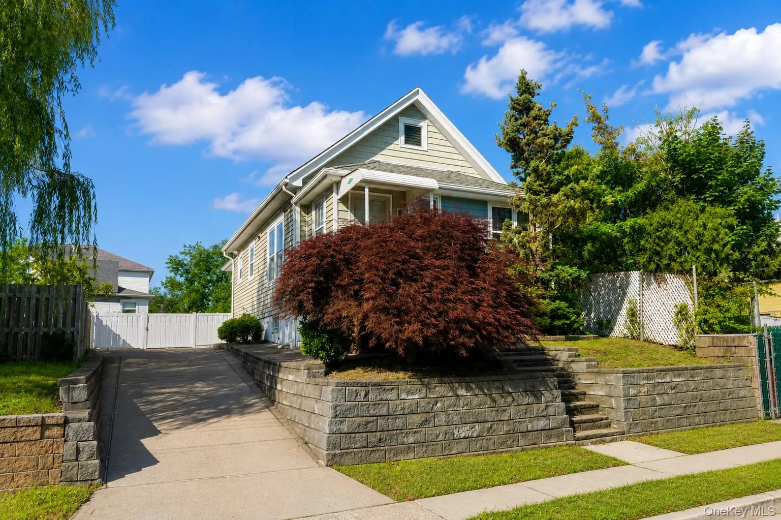 Classic Colonial-style residence featuring a steeply pitched gable roof with dormer window, horizontal siding exterior, and a covered front porch with classical columns Classic Colonial-style residence featuring a steeply pitched gable roof with dormer window, horizontal siding exterior, and a covered front porch with classical columns