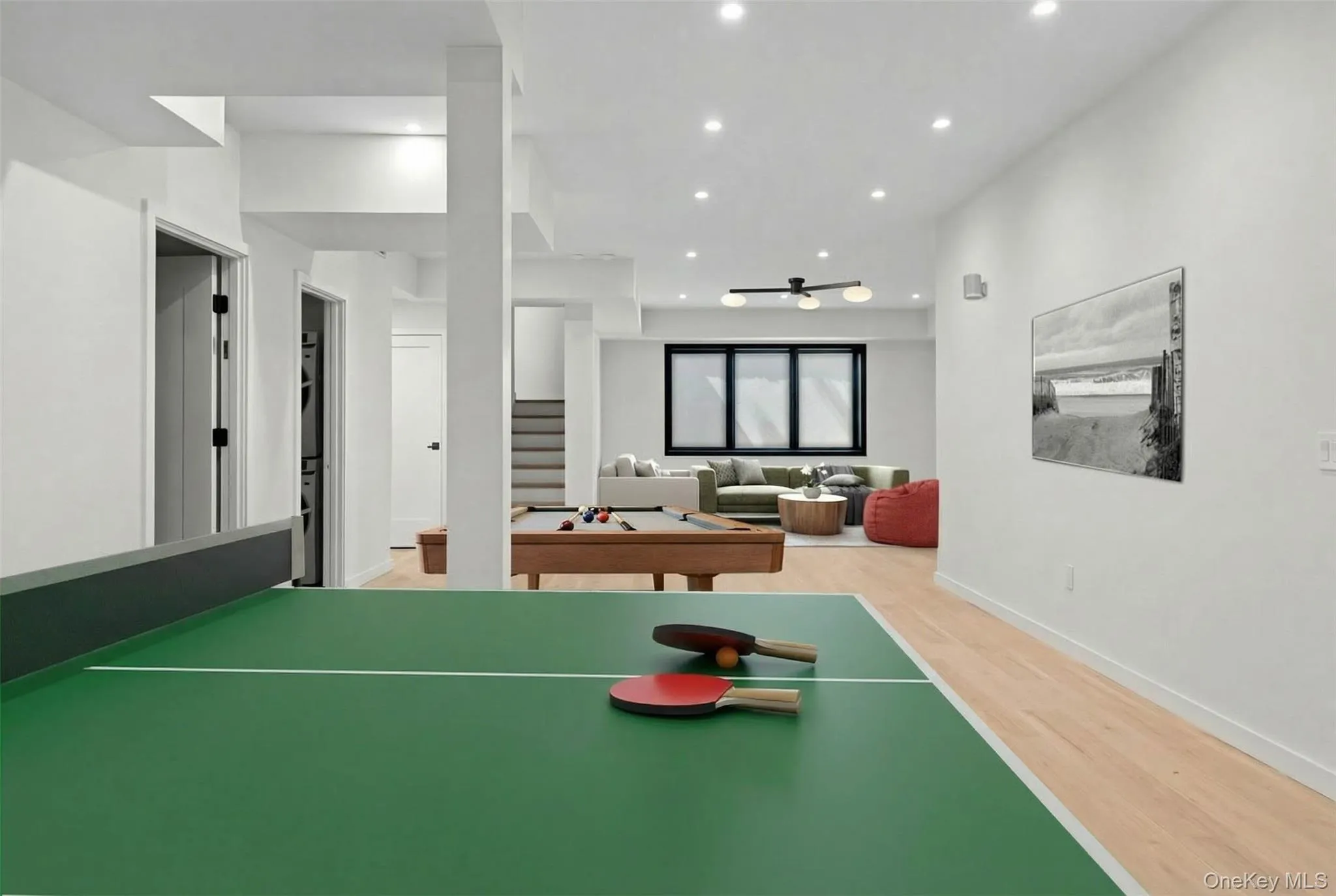 Recreational recreation room featuring a professional-grade ping pong table with wood-finish flooring, recessed ceiling lighting, and an open layout that extends into the adjacent living areas Recreational recreation room featuring a professional-grade ping pong table with wood-finish flooring, recessed ceiling lighting, and an open layout that extends into the adjacent living areas