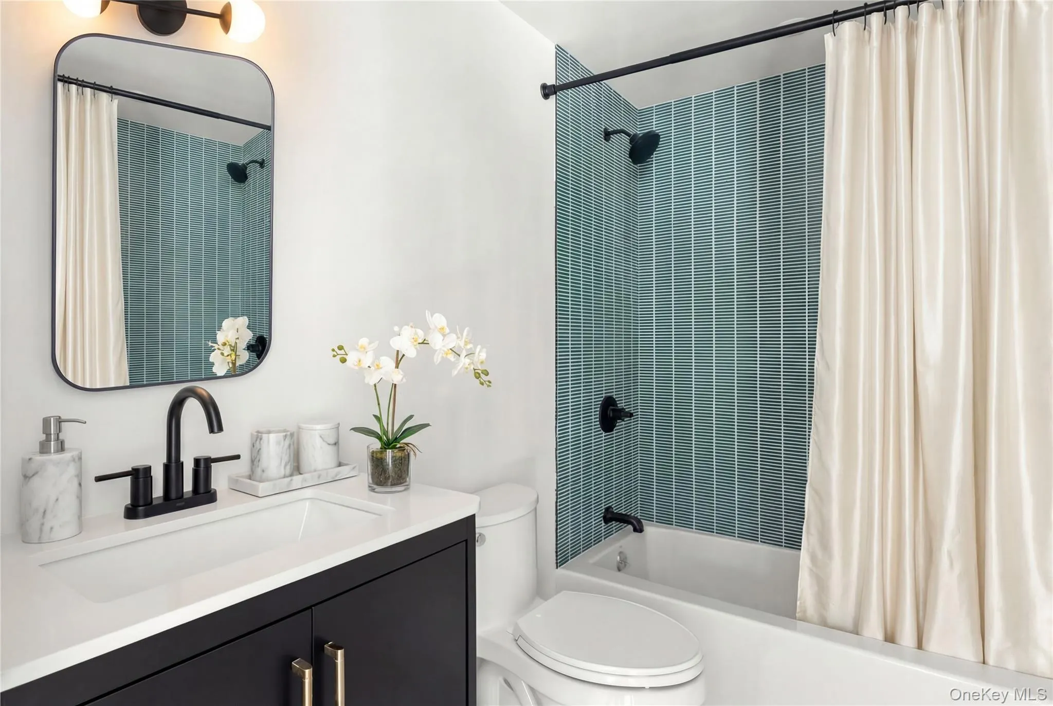 Bathroom featuring a black vanity, white countertop, rectangular basin, matte black faucet, and a tiled shower surround Bathroom featuring a black vanity, white countertop, rectangular basin, matte black faucet, and a tiled shower surround