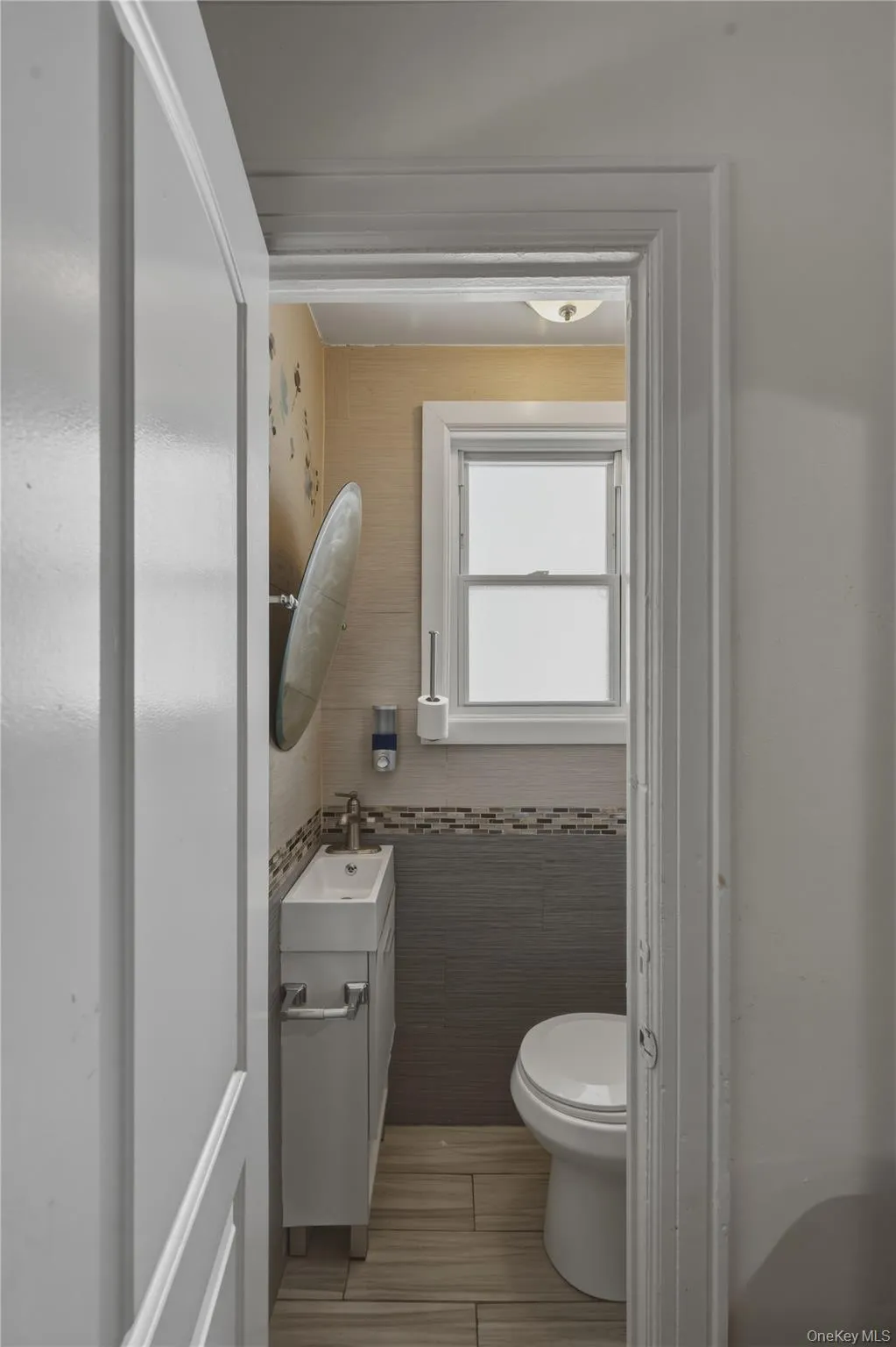 Compact bathroom featuring a window, tile flooring, wall-mounted sink vanity, and a ceiling-mounted light fixture Compact bathroom featuring a window, tile flooring, wall-mounted sink vanity, and a ceiling-mounted light fixture