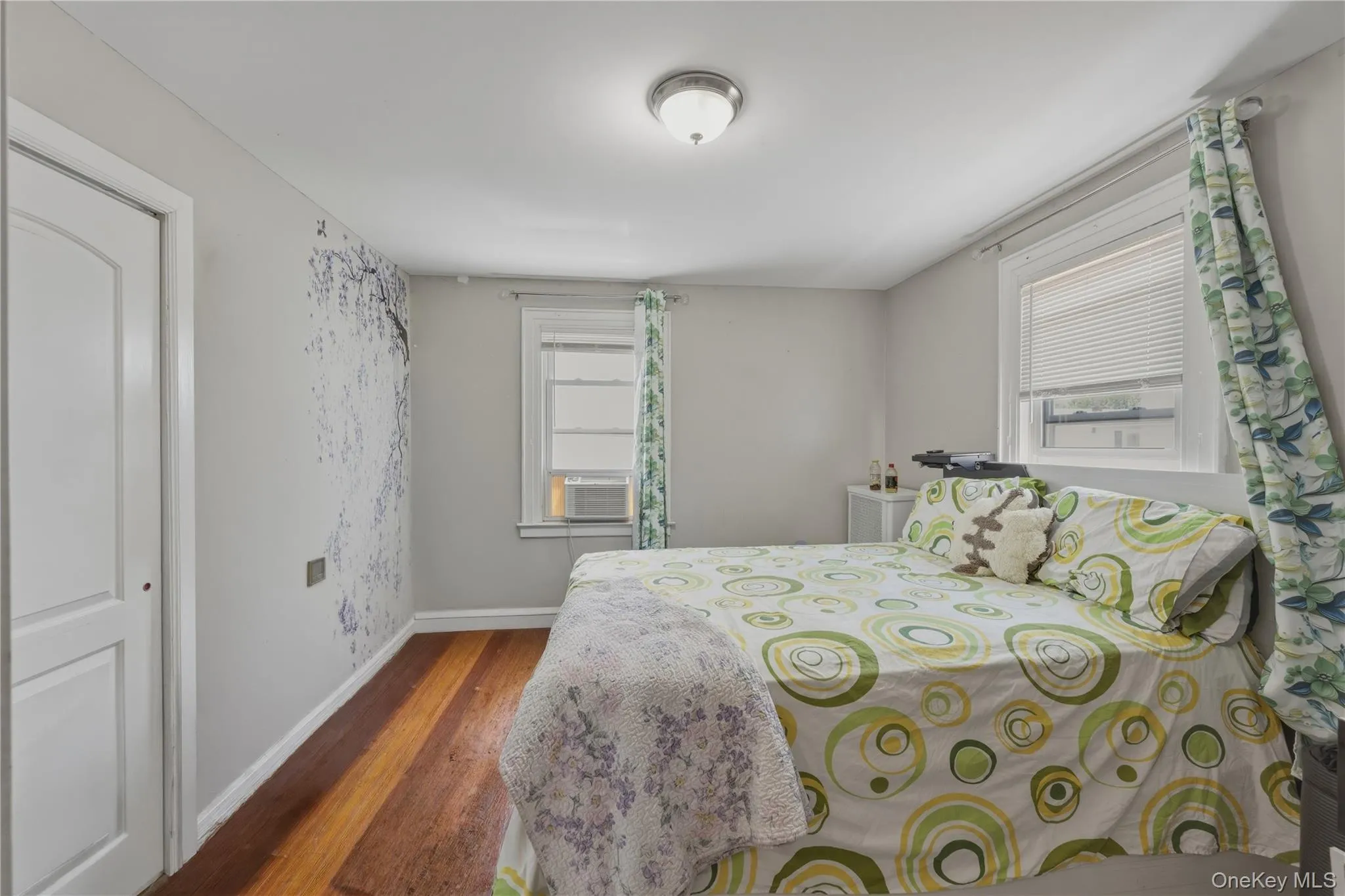 Wood-finish flooring, white trim, and two windows with blinds Wood-finish flooring, white trim, and two windows with blinds