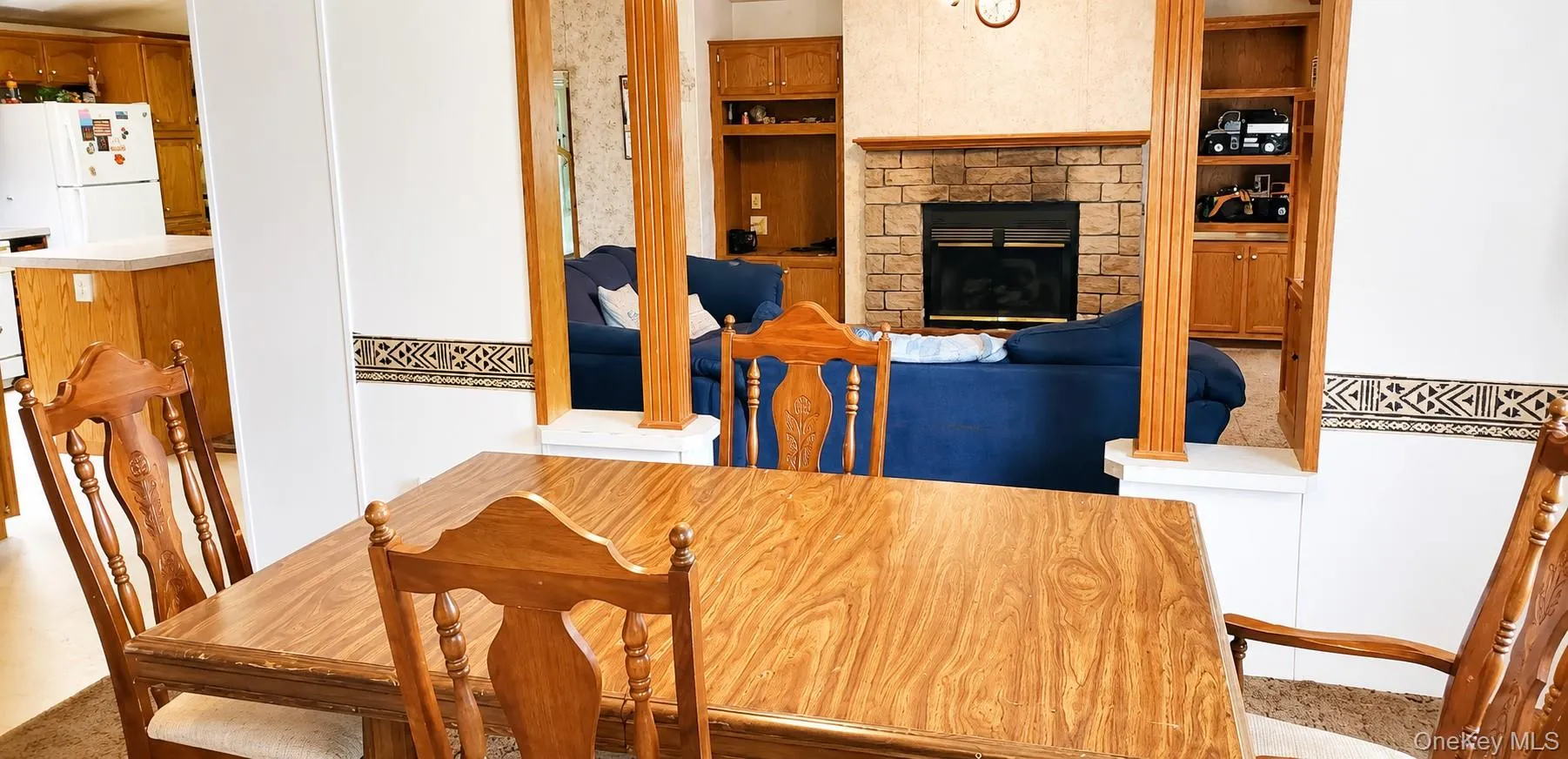 Stone-faced fireplace with a wood mantel, built-in shelving, and wood-finish cabinetry Stone-faced fireplace with a wood mantel, built-in shelving, and wood-finish cabinetry