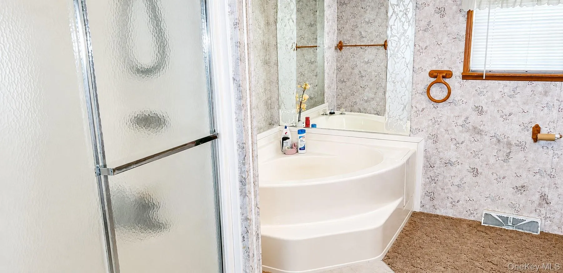 Frosted glass shower enclosure, corner soaking tub, integrated tub steps, and a wall-mounted mirror Frosted glass shower enclosure, corner soaking tub, integrated tub steps, and a wall-mounted mirror