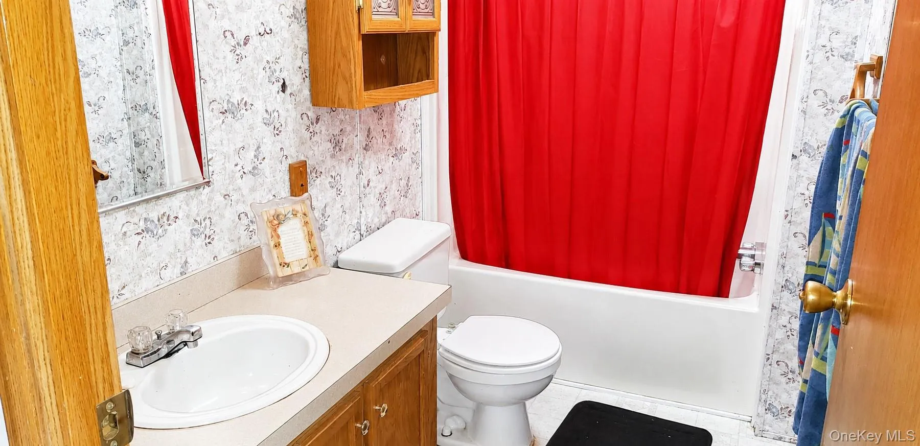 Bathroom featuring a built-in vanity with an integrated sink, a wall-mounted mirror, a toilet, a bathtub, and a wall-mounted wood-finish cabinet Bathroom featuring a built-in vanity with an integrated sink, a wall-mounted mirror, a toilet, a bathtub, and a wall-mounted wood-finish cabinet