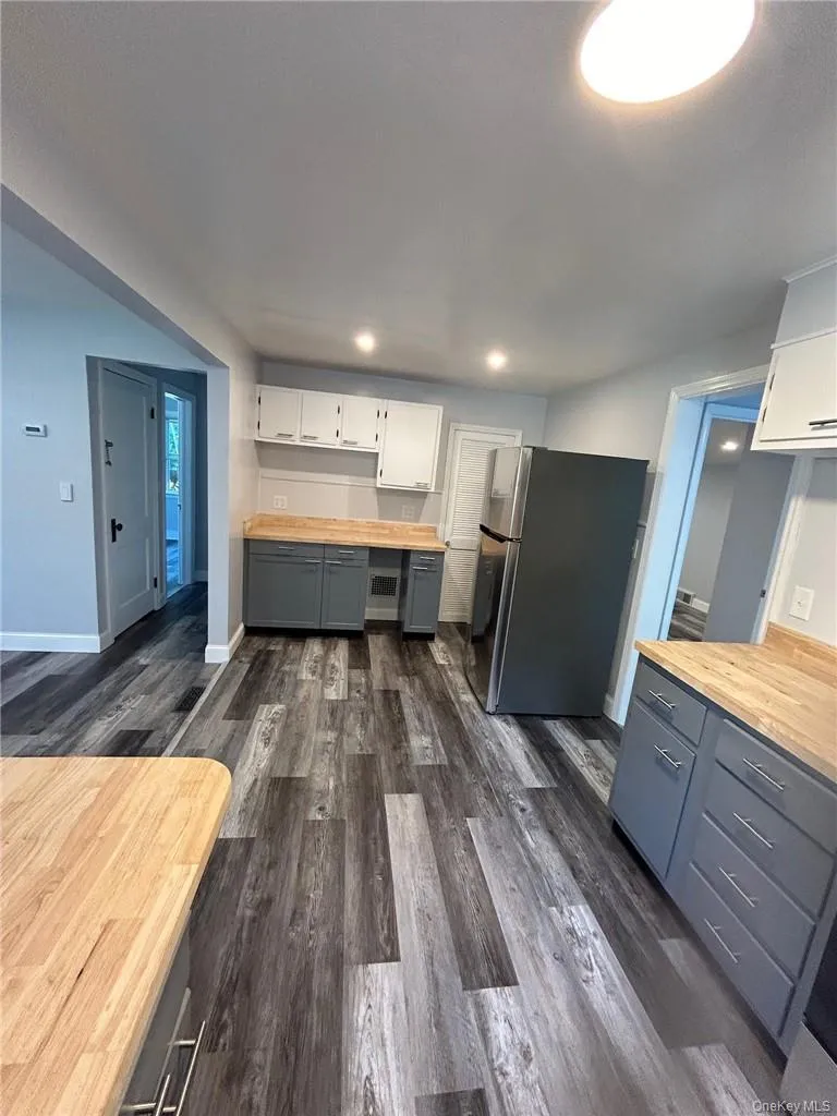 Kitchen featuring wooden counters, white cabinetry, dark hardwood / wood-style flooring, gray cabinets, and stainless steel fridge Kitchen featuring wooden counters, white cabinetry, dark hardwood / wood-style flooring, gray cabinets, and stainless steel fridge