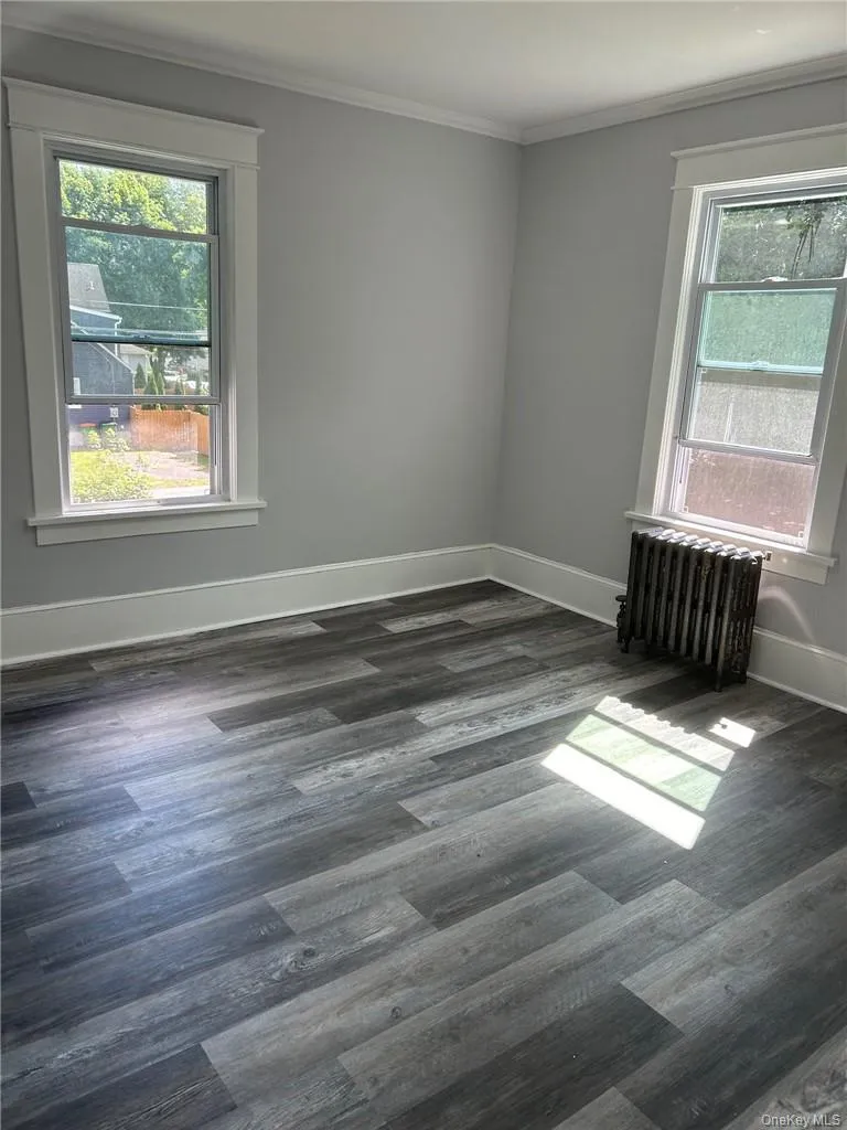 Bedroom with ornamental molding, contemporary gray flooring, a wealth of natural light, and radiator heating unit Bedroom with ornamental molding, contemporary gray flooring, a wealth of natural light, and radiator heating unit