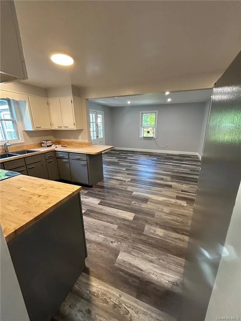 Kitchen with butcher block countertops, sink, easy to clean gray vinyl plank floors, and gray cabinetry Kitchen with butcher block countertops, sink, easy to clean gray vinyl plank floors, and gray cabinetry