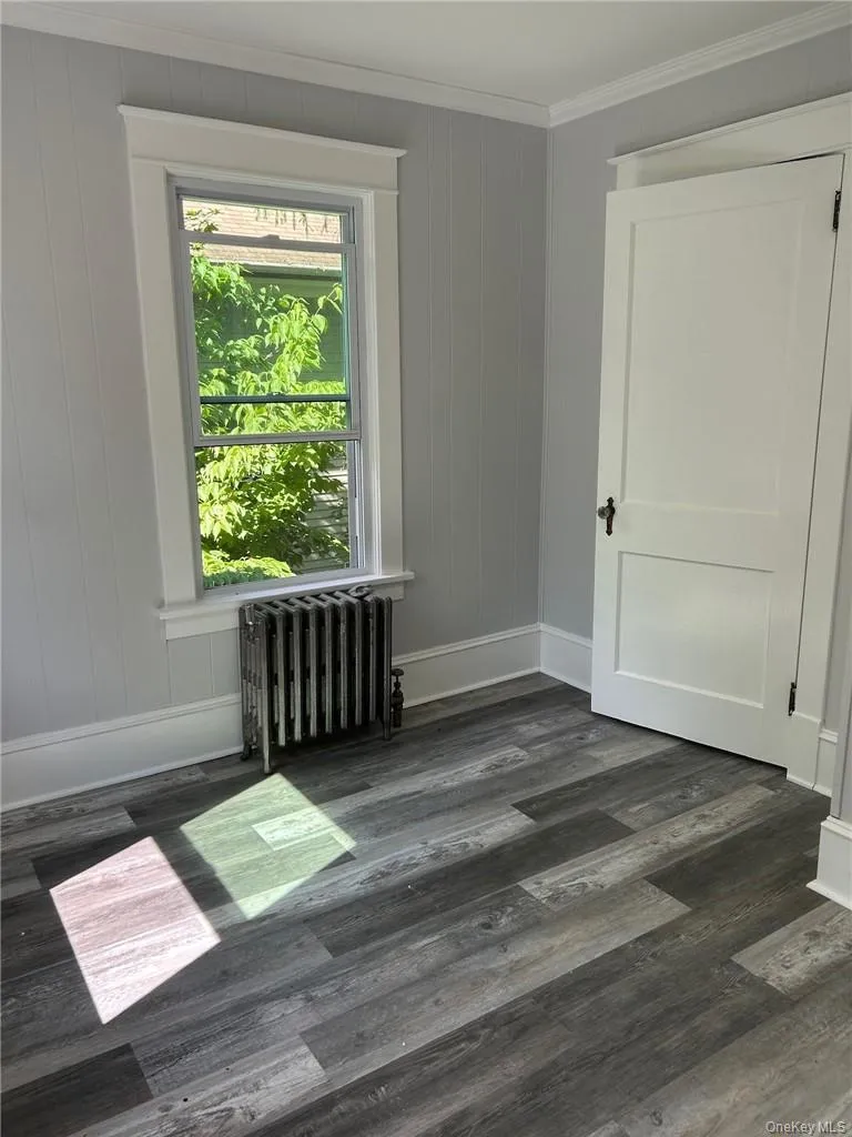 Bedroom featuring radiator heating unit, contemporary gray flooring, and ornamental molding Bedroom featuring radiator heating unit, contemporary gray flooring, and ornamental molding