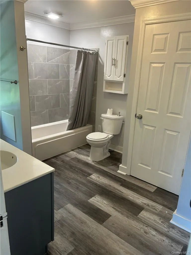 Large Full bathroom featuring shower / tub combo, toilet, contemporary floors, and vanity Large Full bathroom featuring shower / tub combo, toilet, contemporary floors, and vanity