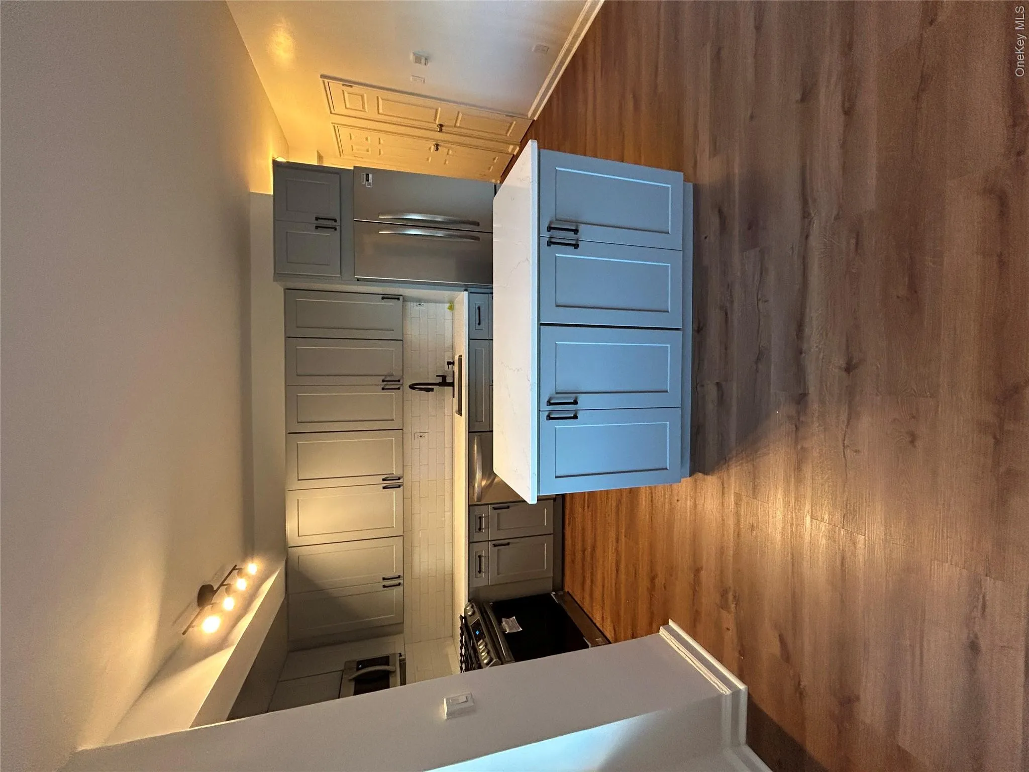 Kitchen with stove, dark wood-type flooring, fridge, gray cabinets, and tasteful backsplash Kitchen with stove, dark wood-type flooring, fridge, gray cabinets, and tasteful backsplash