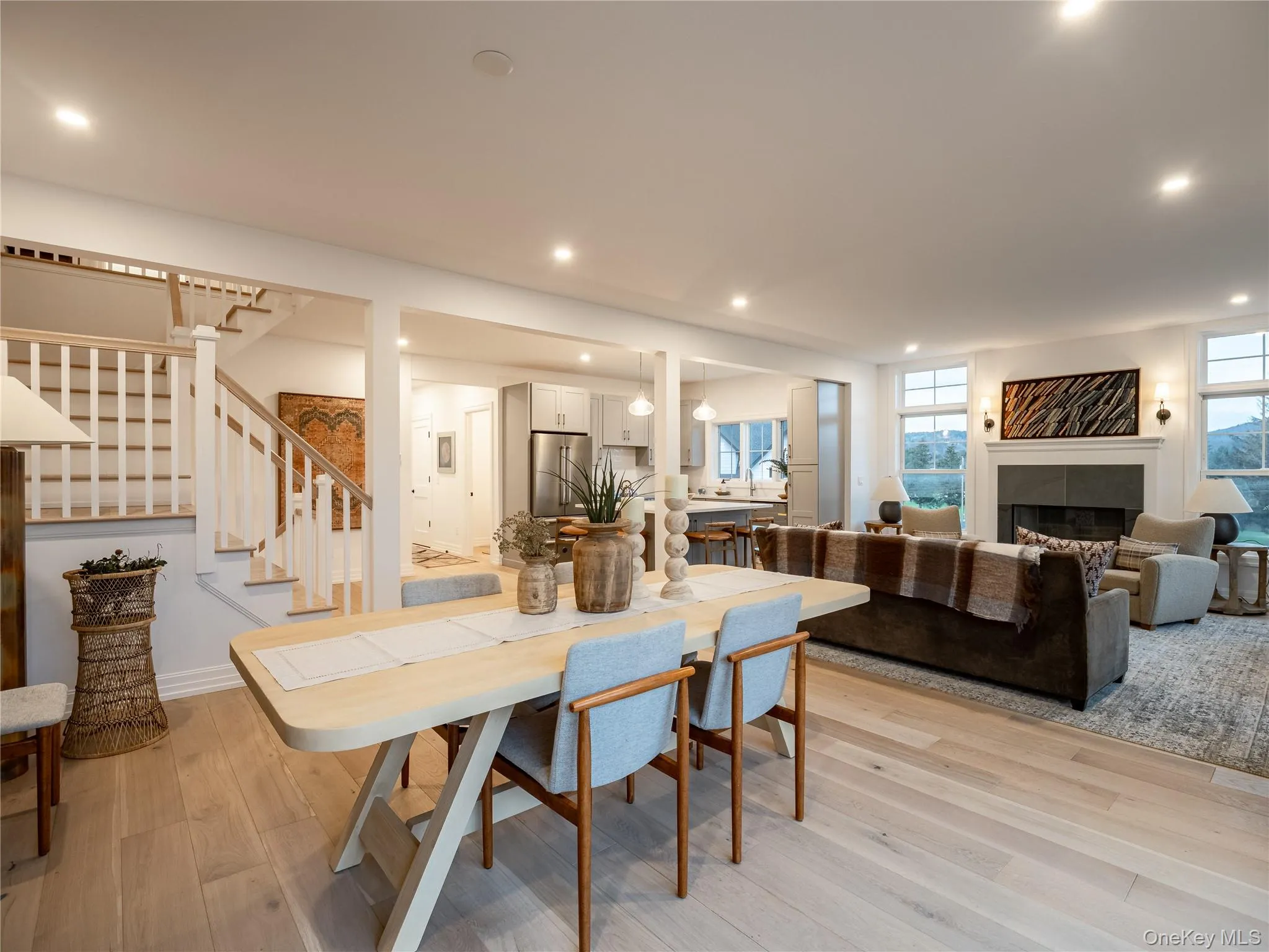 Dining area featuring a tile fireplace, stairs, light wood finished floors, and recessed lighting Dining area featuring a tile fireplace, stairs, light wood finished floors, and recessed lighting