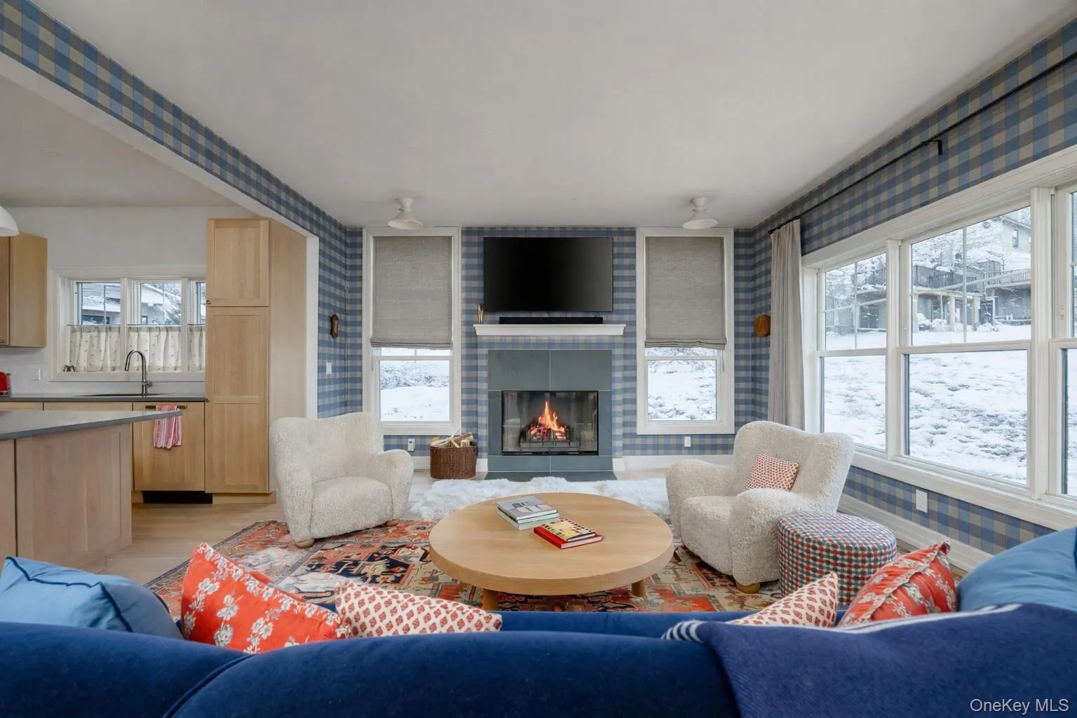 Living area with a brick fireplace, wallpapered walls, and plenty of natural light Living area with a brick fireplace, wallpapered walls, and plenty of natural light