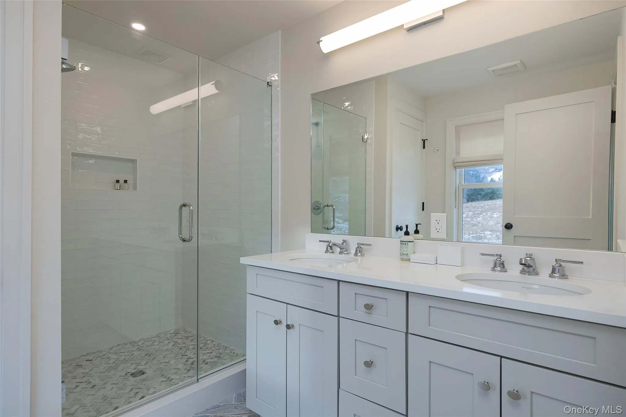 Bathroom with double vanity, a stall shower, and marble look tile flooring Bathroom with double vanity, a stall shower, and marble look tile flooring