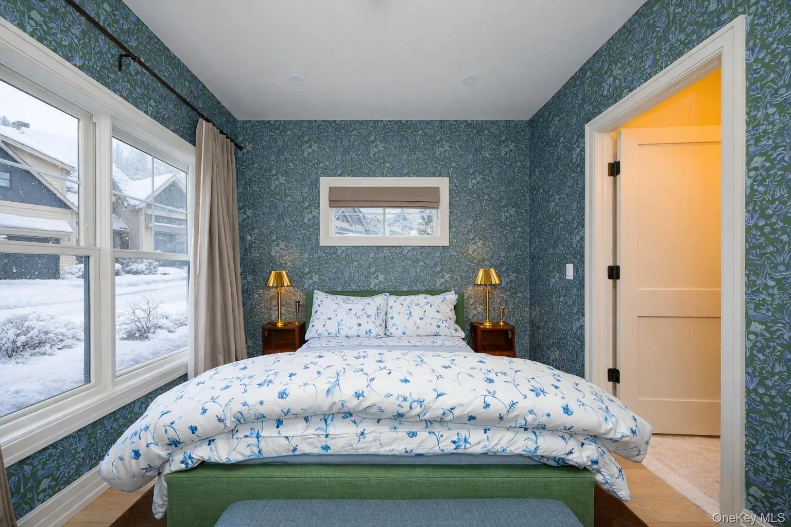 Bedroom featuring wallpapered walls, multiple windows, and wood finished floors Bedroom featuring wallpapered walls, multiple windows, and wood finished floors