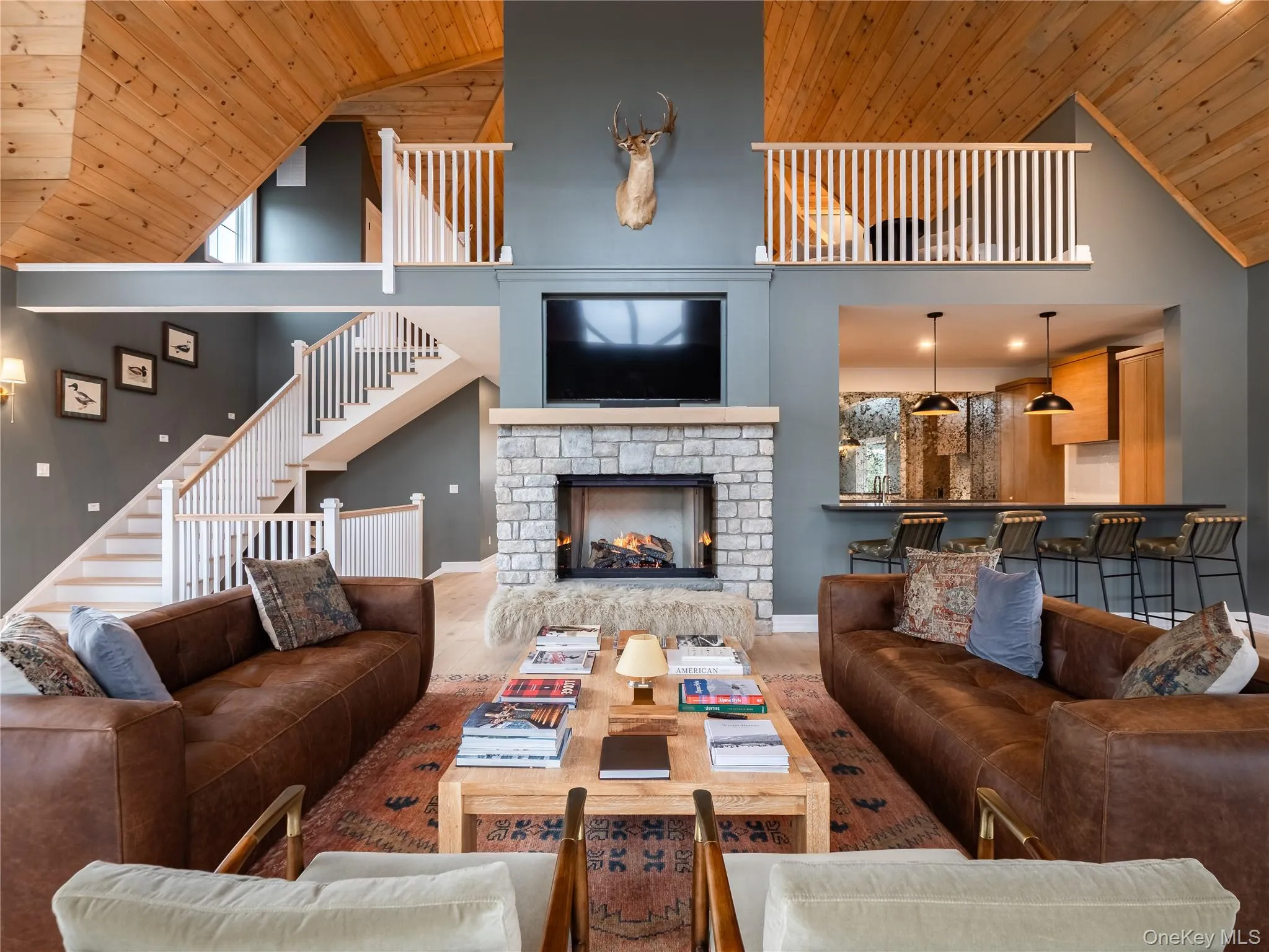 Living room featuring wooden ceiling, a warm lit fireplace, high vaulted ceiling, and stairway Living room featuring wooden ceiling, a warm lit fireplace, high vaulted ceiling, and stairway
