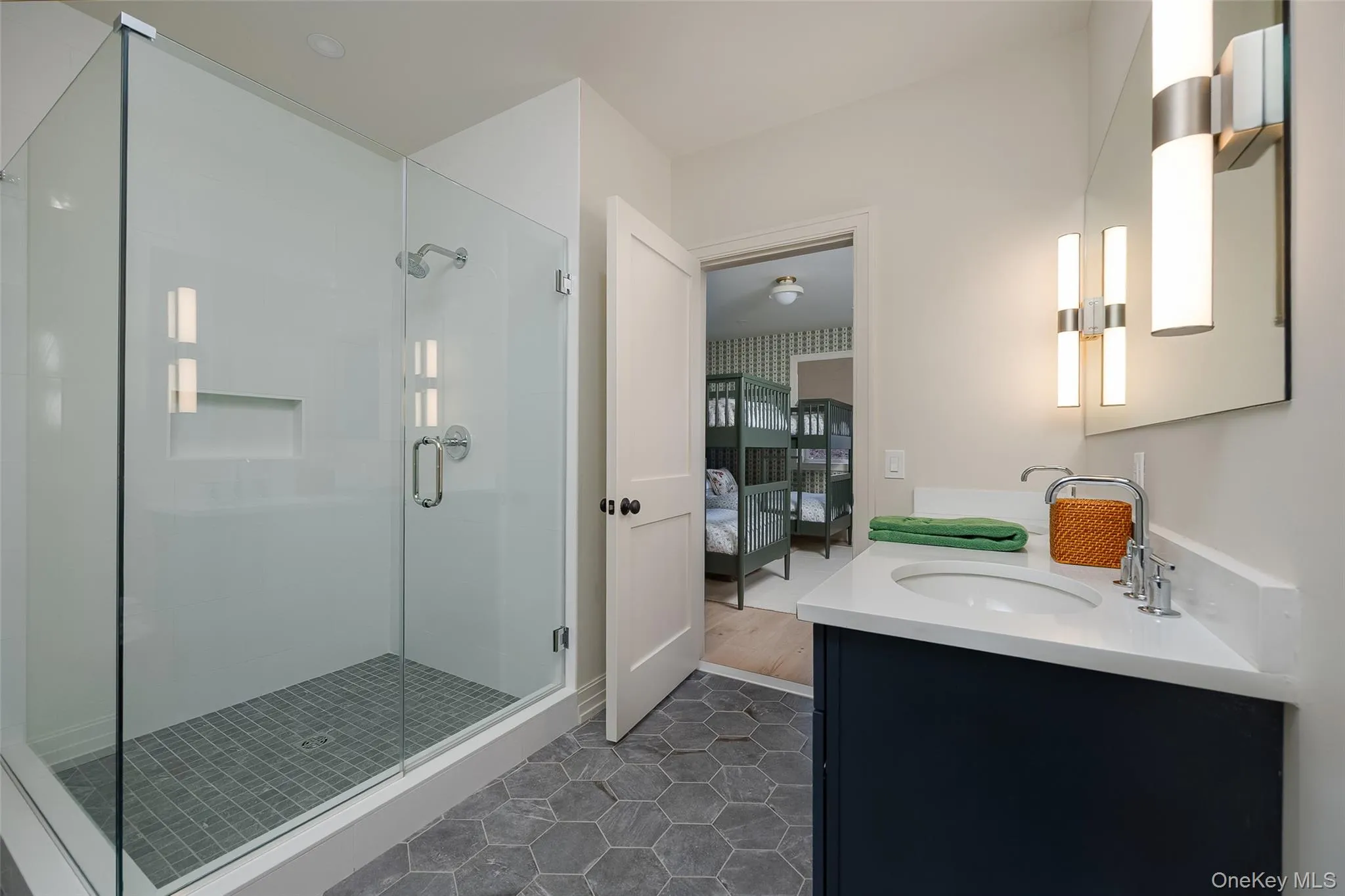 Bathroom featuring ensuite bath, double vanity, a shower stall, and dark tile patterned floors Bathroom featuring ensuite bath, double vanity, a shower stall, and dark tile patterned floors