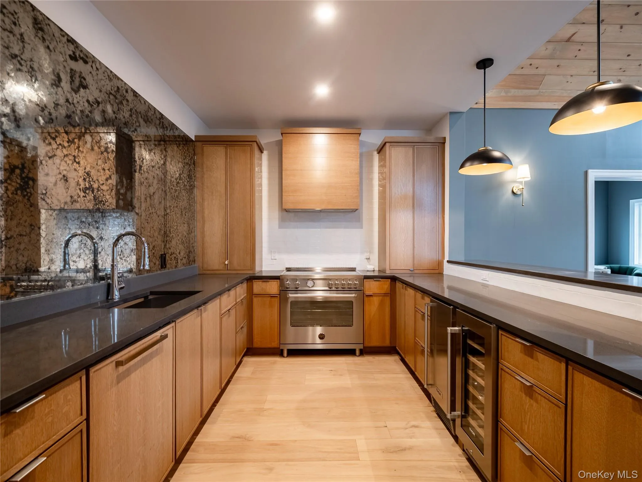 Kitchen with high end stainless steel range oven, dark stone countertops, decorative light fixtures, brown cabinets, and light wood-style floors Kitchen with high end stainless steel range oven, dark stone countertops, decorative light fixtures, brown cabinets, and light wood-style floors