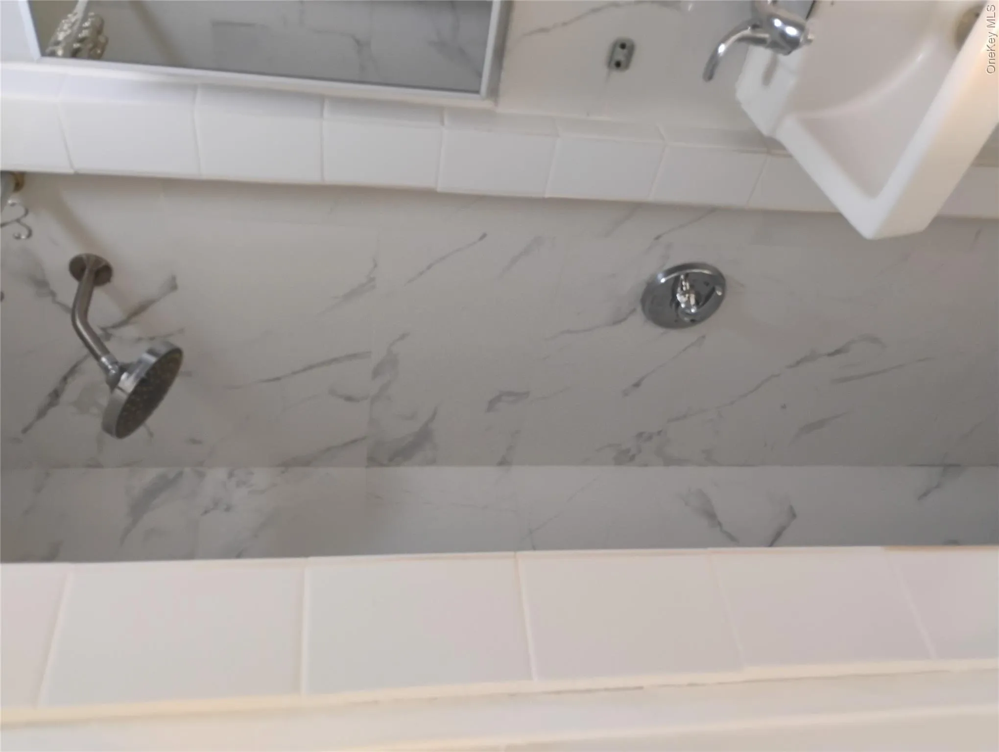 Shower stall with marble-look wall tiling and a chrome rain shower head Shower stall with marble-look wall tiling and a chrome rain shower head