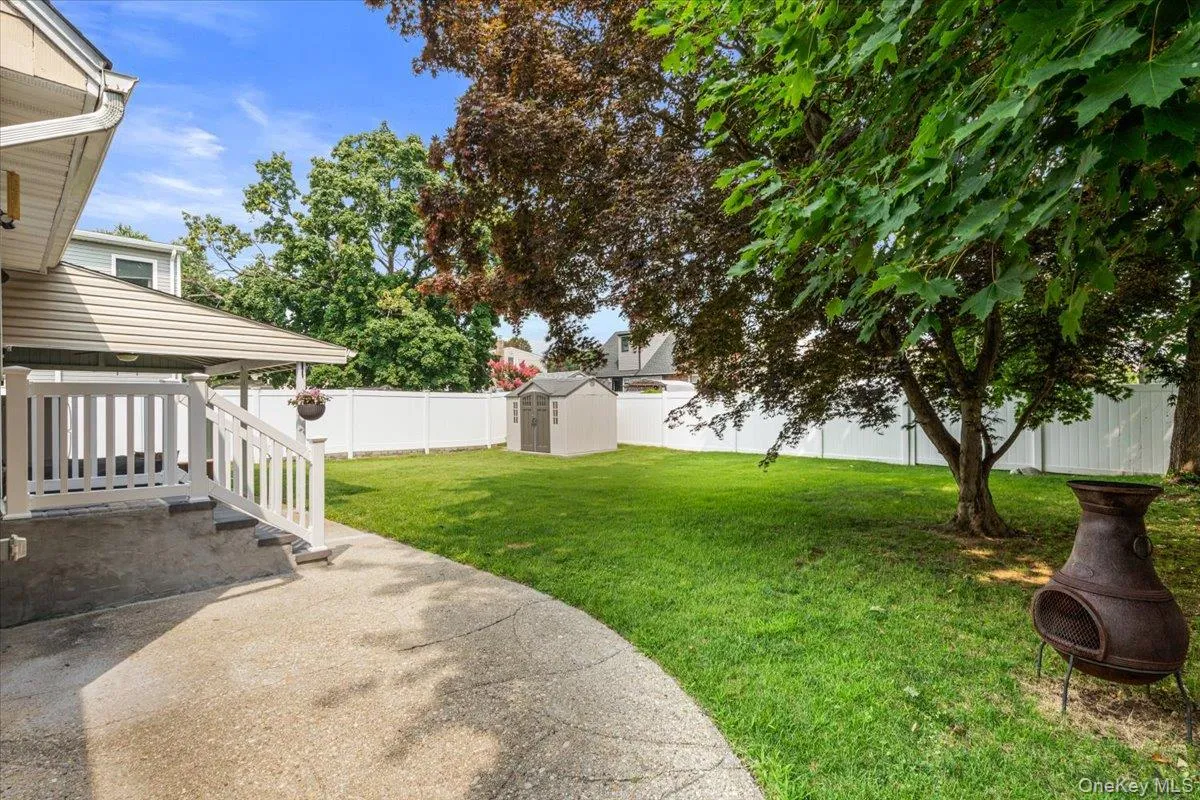 Expansive backyard with a manicured lawn, established trees, and a white privacy fence Expansive backyard with a manicured lawn, established trees, and a white privacy fence