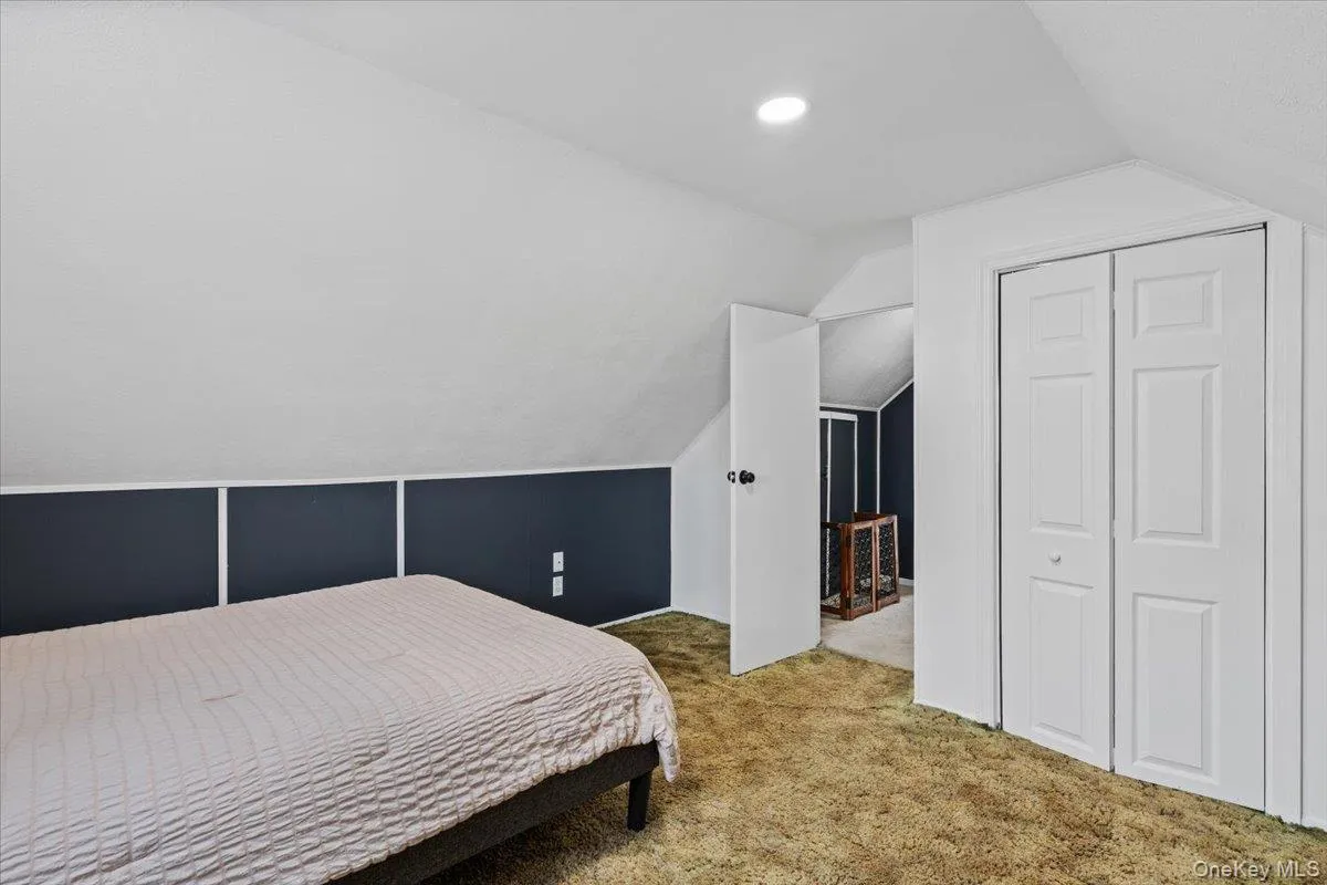Sloped ceiling with recessed lighting, paneled accent wall, and bi-fold closet doors Sloped ceiling with recessed lighting, paneled accent wall, and bi-fold closet doors