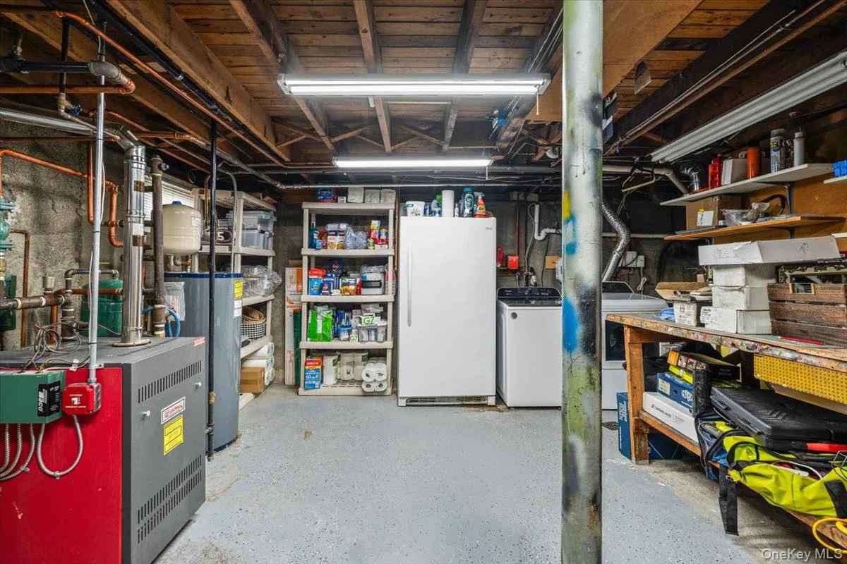 Concrete flooring, exposed utility piping, and a workbench with shelving Concrete flooring, exposed utility piping, and a workbench with shelving