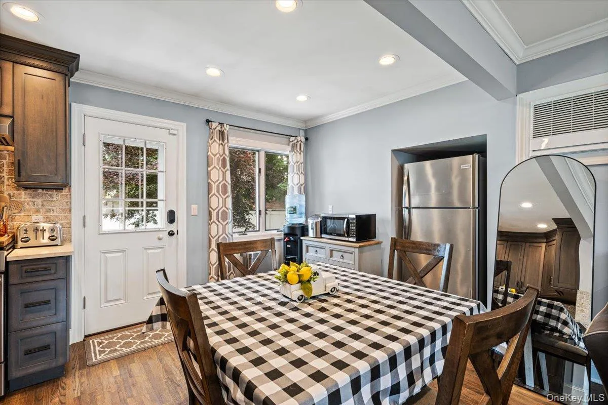 Wood-finish flooring, recessed lighting, French pane door, stainless steel refrigerator, and wood-finish cabinetry Wood-finish flooring, recessed lighting, French pane door, stainless steel refrigerator, and wood-finish cabinetry