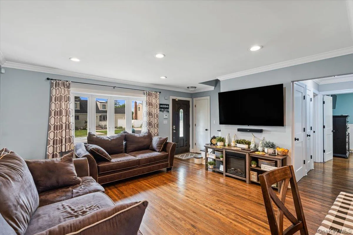 Hardwood flooring, recessed lighting, crown molding, bay window, and a dark wood-finish entry door Hardwood flooring, recessed lighting, crown molding, bay window, and a dark wood-finish entry door