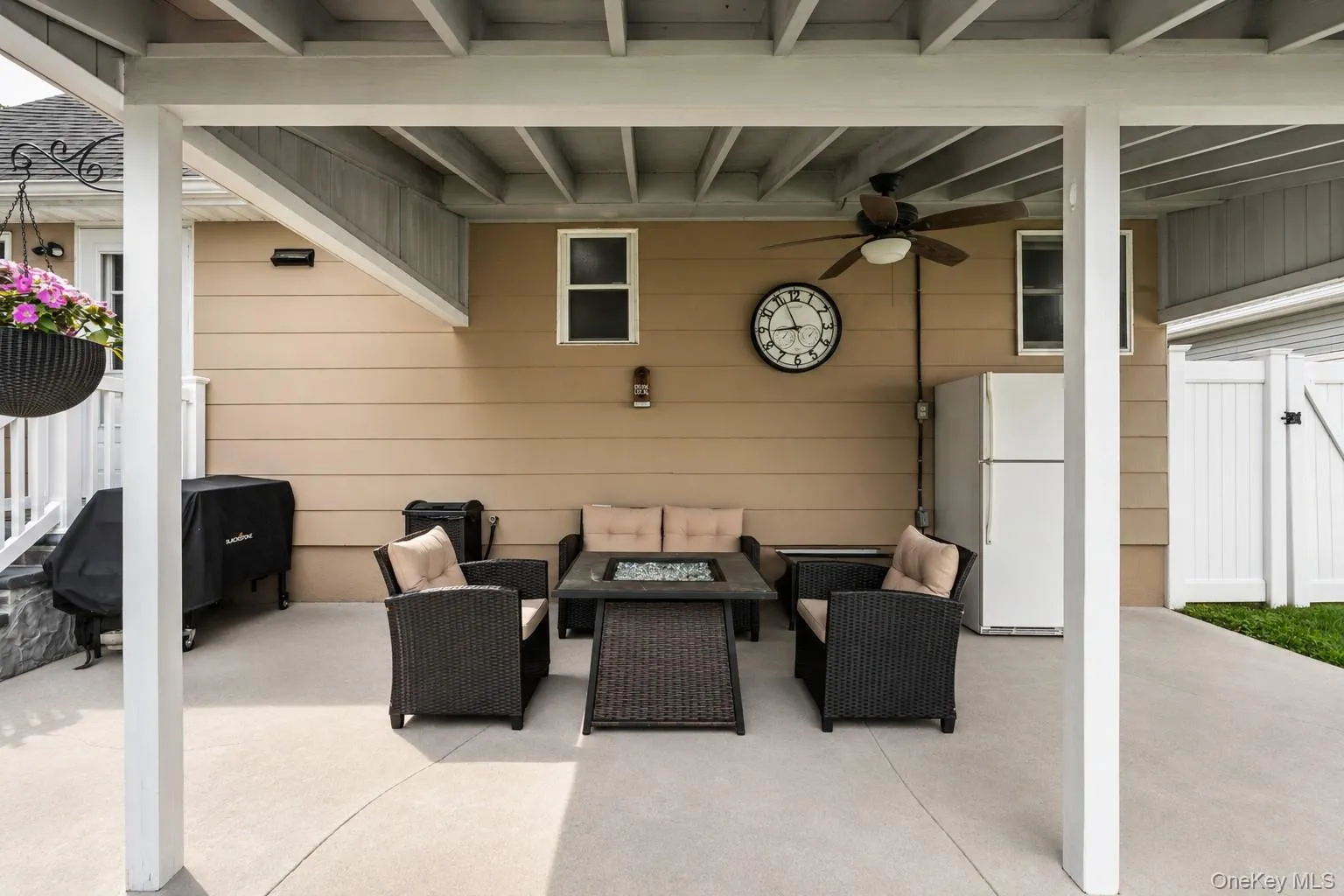 Covered concrete patio featuring an outdoor ceiling fan, integrated lighting, and a white privacy fence Covered concrete patio featuring an outdoor ceiling fan, integrated lighting, and a white privacy fence
