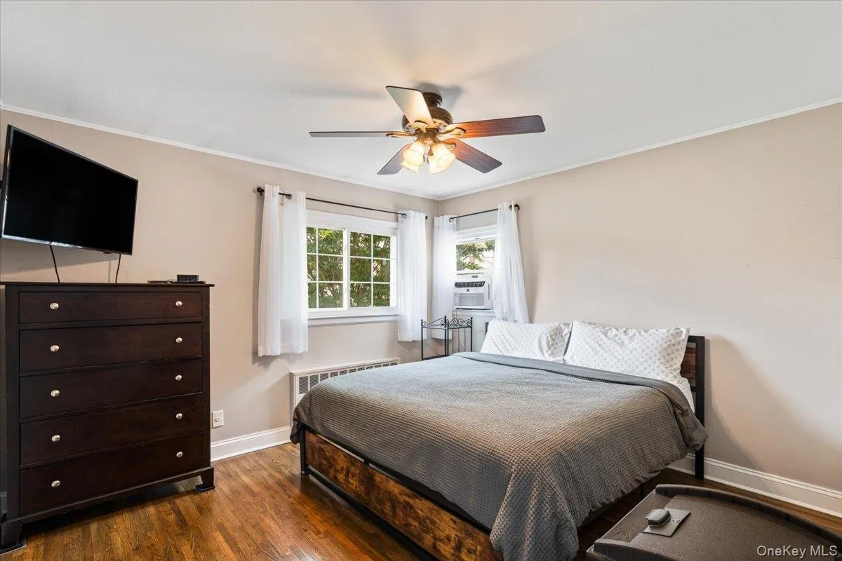 Wood-finish flooring, ceiling fan with integrated lighting, and multiple windows providing natural illumination Wood-finish flooring, ceiling fan with integrated lighting, and multiple windows providing natural illumination