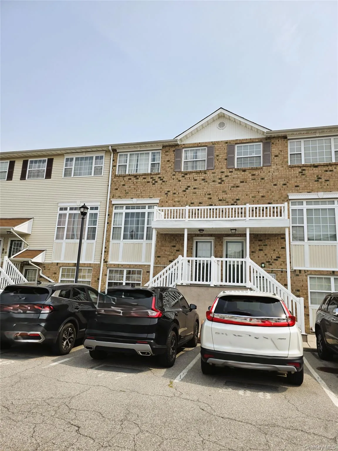 Brick and vinyl exterior townhome with white railed entry deck and multi-pane windows Brick and vinyl exterior townhome with white railed entry deck and multi-pane windows