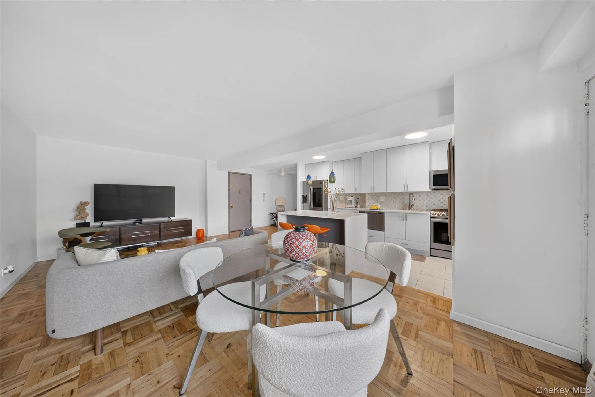 Wood-finish flooring throughout, modern kitchen with white cabinetry, stainless steel appliances, and a central island Wood-finish flooring throughout, modern kitchen with white cabinetry, stainless steel appliances, and a central island