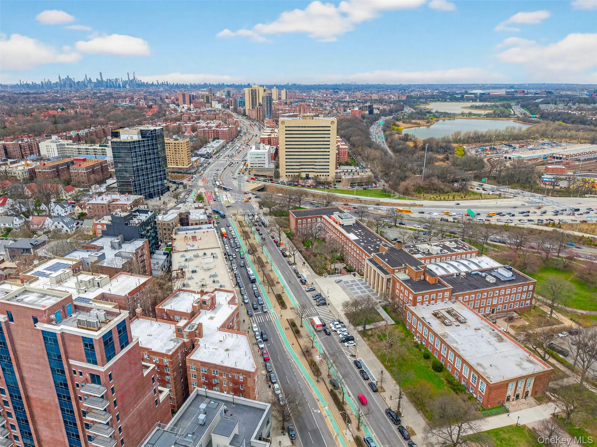 Aerial perspective of urban landscape featuring multiple high-rise buildings, a multi-lane thoroughfare, and a distant body of water Aerial perspective of urban landscape featuring multiple high-rise buildings, a multi-lane thoroughfare, and a distant body of water