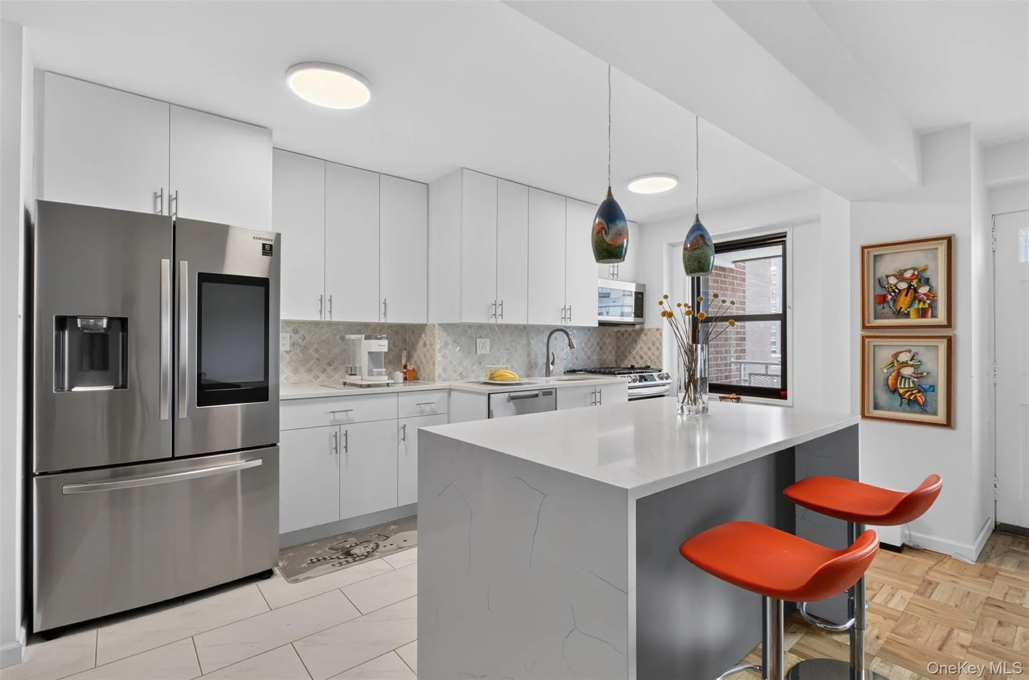 Kitchen featuring a stainless steel refrigerator, white cabinetry with silver hardware, and a center island with a light-toned countertop Kitchen featuring a stainless steel refrigerator, white cabinetry with silver hardware, and a center island with a light-toned countertop