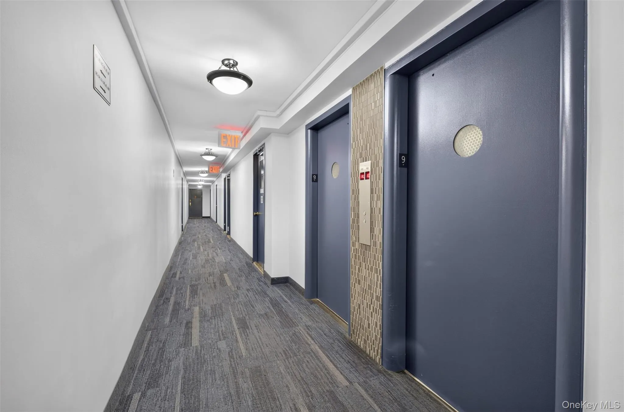 Corridor featuring patterned carpet flooring, flush-mount ceiling lights, light wall finishes, and dark paneled doors Corridor featuring patterned carpet flooring, flush-mount ceiling lights, light wall finishes, and dark paneled doors