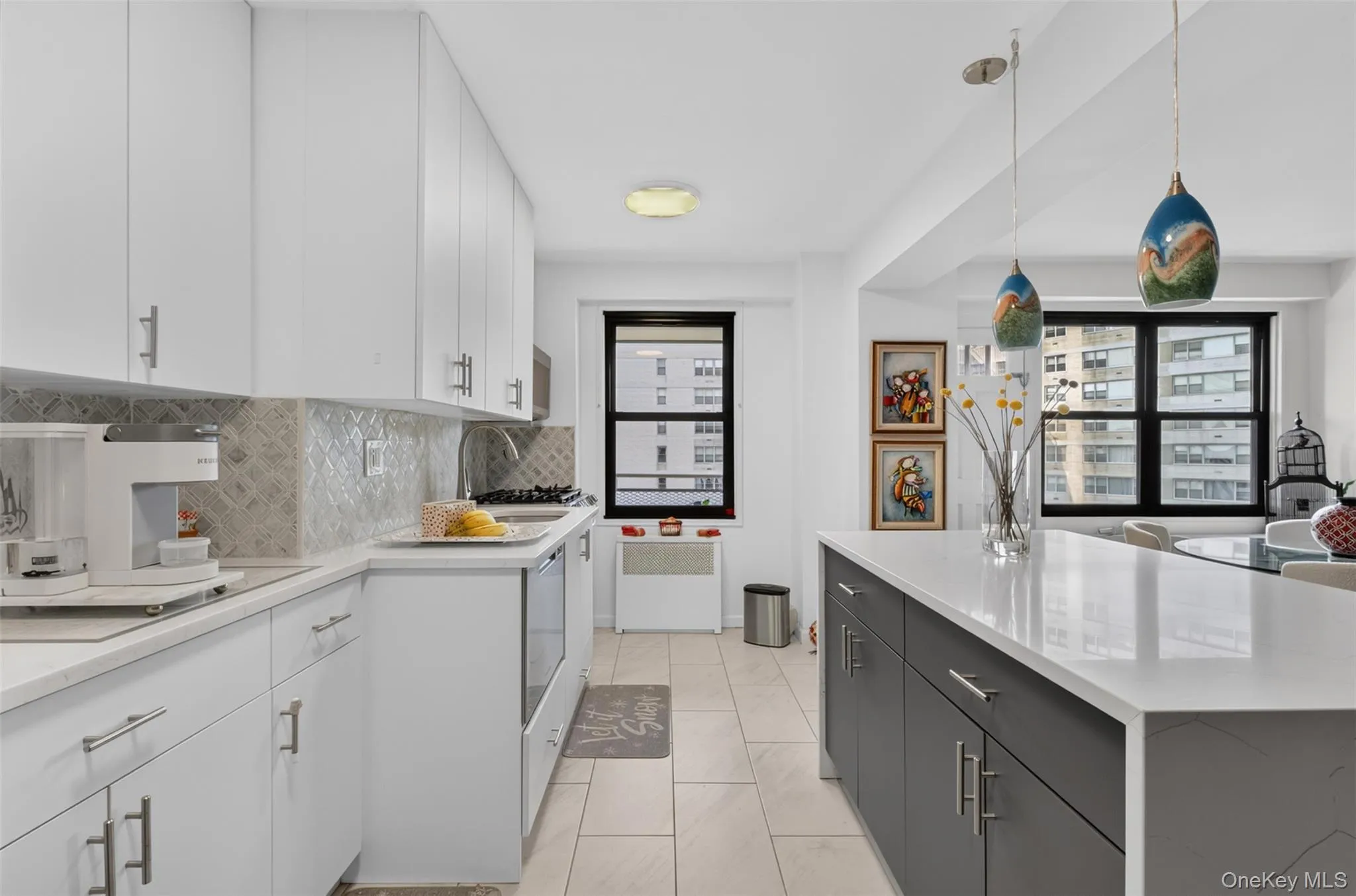 Modern kitchen featuring white upper cabinetry, a patterned tile backsplash, and light-toned countertops Modern kitchen featuring white upper cabinetry, a patterned tile backsplash, and light-toned countertops