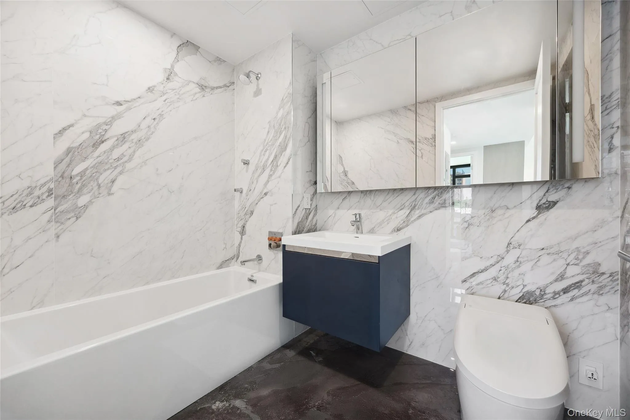 Bathroom featuring tile walls, toilet, shower / bath combination, vanity, and marble finish floors Bathroom featuring tile walls, toilet, shower / bath combination, vanity, and marble finish floors