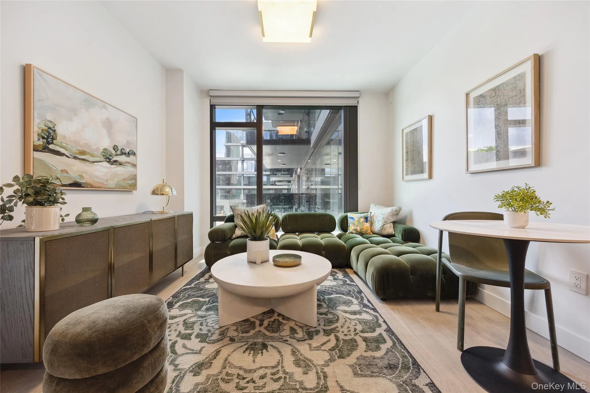 Living area featuring light wood-style flooring, baseboards, and a wall of windows Living area featuring light wood-style flooring, baseboards, and a wall of windows