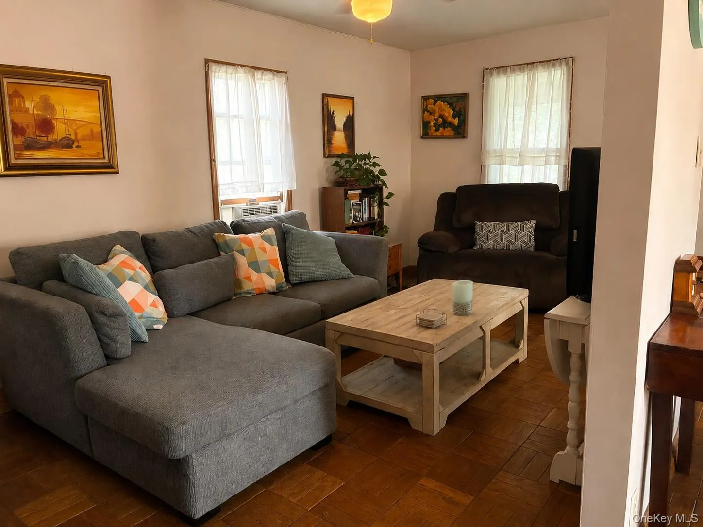 Wood-finish flooring with a checkered pattern, ceiling fan with integrated lighting, and a window air conditioning unit Wood-finish flooring with a checkered pattern, ceiling fan with integrated lighting, and a window air conditioning unit