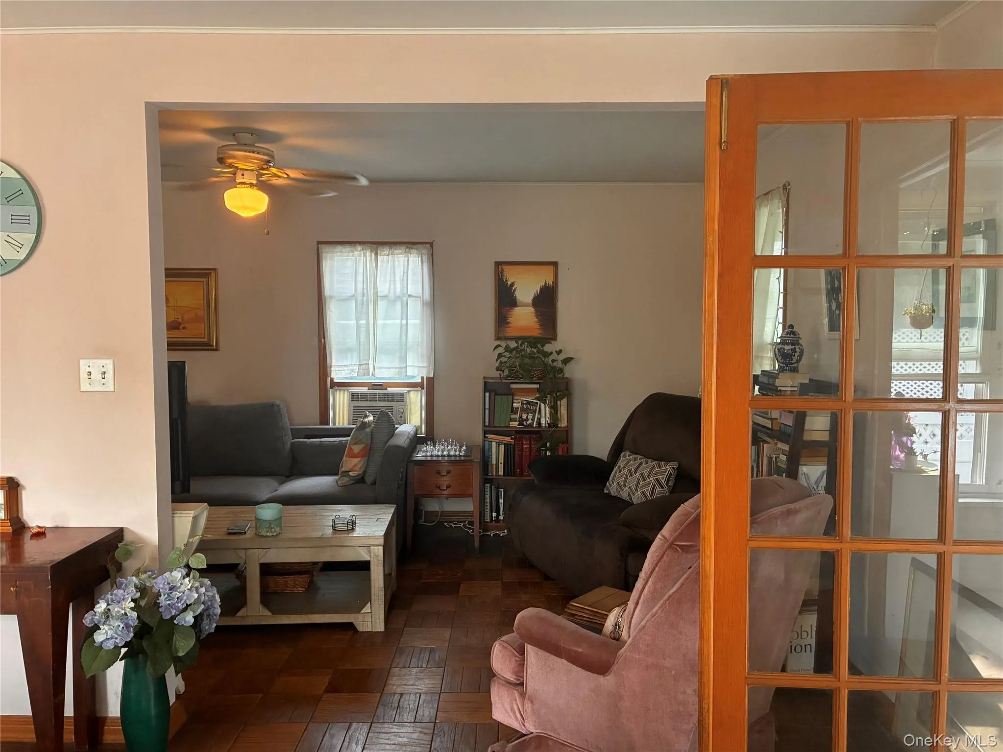 Wood-finish flooring with a checkered pattern, ceiling fan with integrated lighting, and a window air conditioning unit Wood-finish flooring with a checkered pattern, ceiling fan with integrated lighting, and a window air conditioning unit