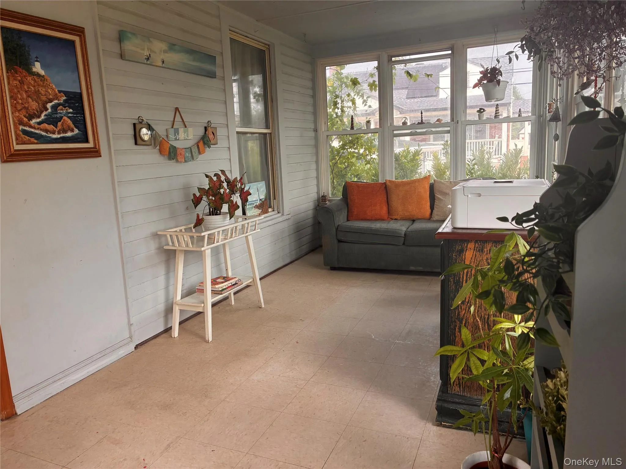 Enclosed sunroom featuring multiple windows, paneled walls, and tiled flooring Enclosed sunroom featuring multiple windows, paneled walls, and tiled flooring