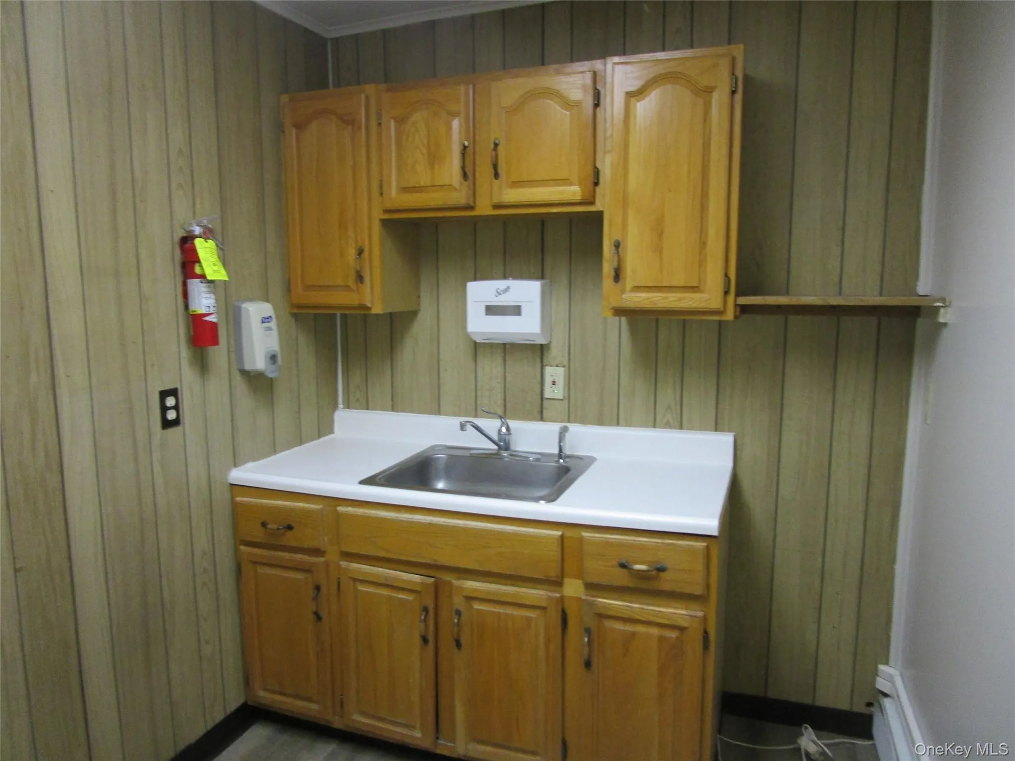Kitchen with wooden walls, light countertops, and a sink Kitchen with wooden walls, light countertops, and a sink