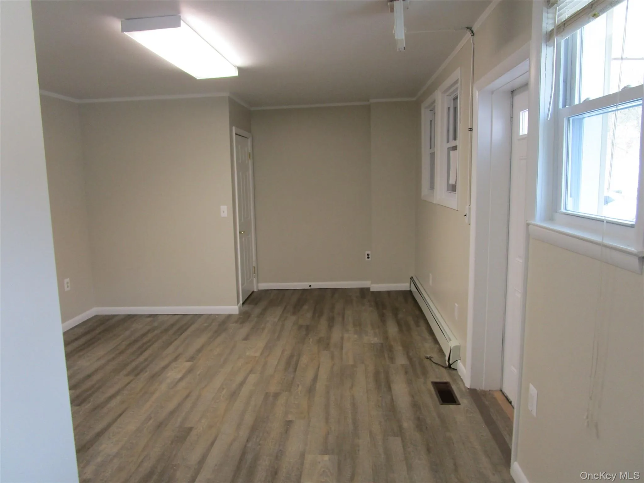 Empty room with visible vents, baseboards, a baseboard radiator, crown molding, and wood finished floors Empty room with visible vents, baseboards, a baseboard radiator, crown molding, and wood finished floors